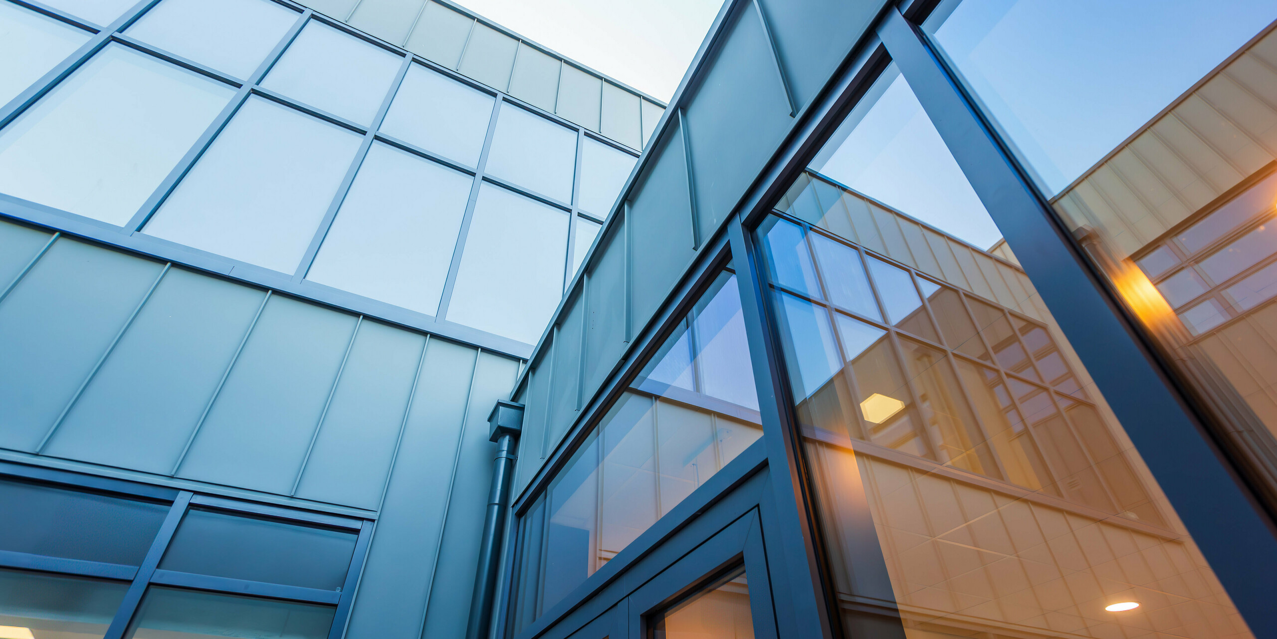 Vue plongeante sur la façade moderne en aluminium PREFALZ en P.10 gris souris du Scoil Mhuire Naofa à Carrigtwohill, en Irlande. De grandes surfaces vitrées et des joints debout précis soulignent l'architecture contemporaine et assurent un design élégant et baigné de lumière.