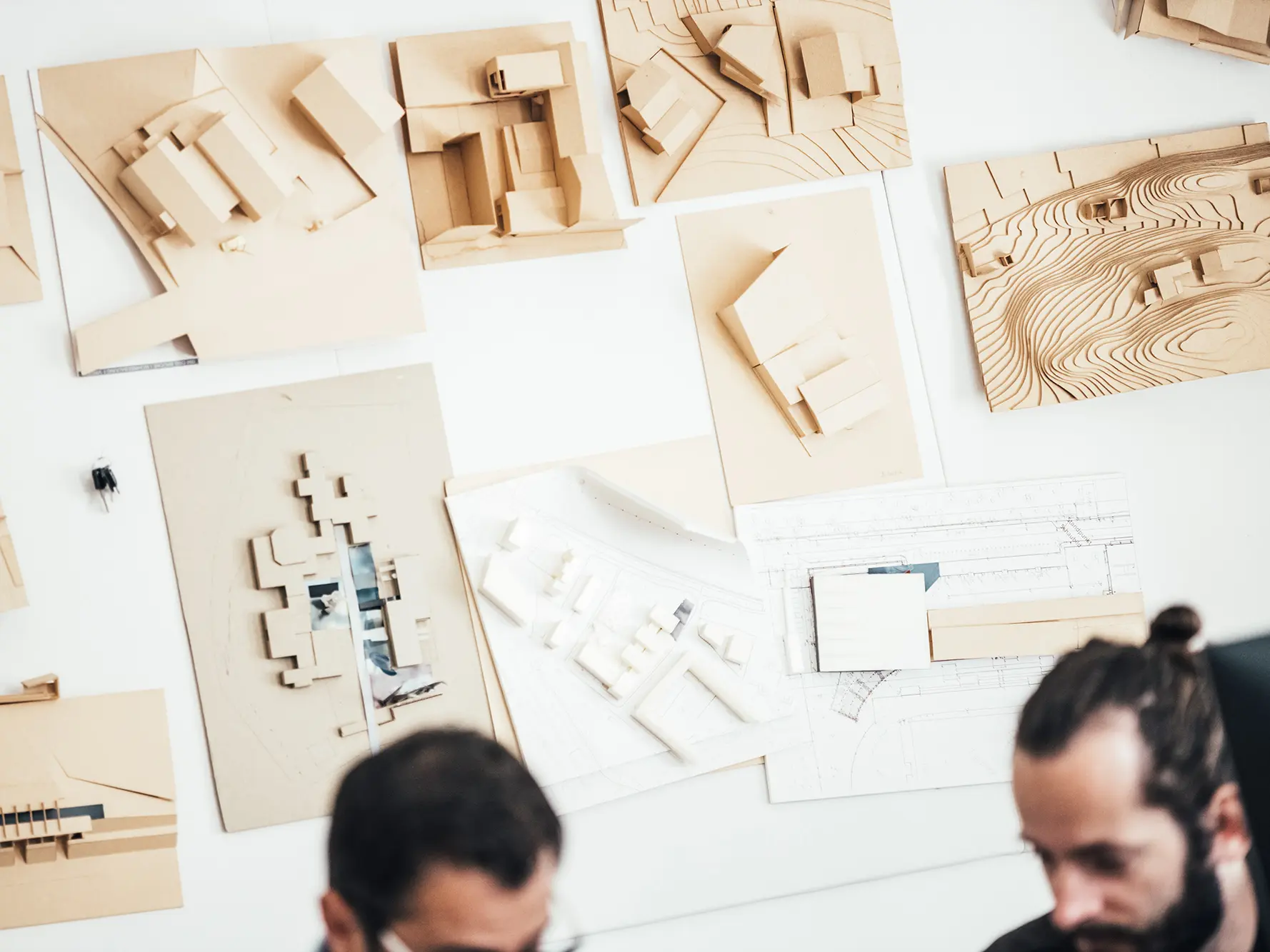 Cliché des modèles architecturaux sur les murs. En flou au premier plan : deux employés du cabinet.