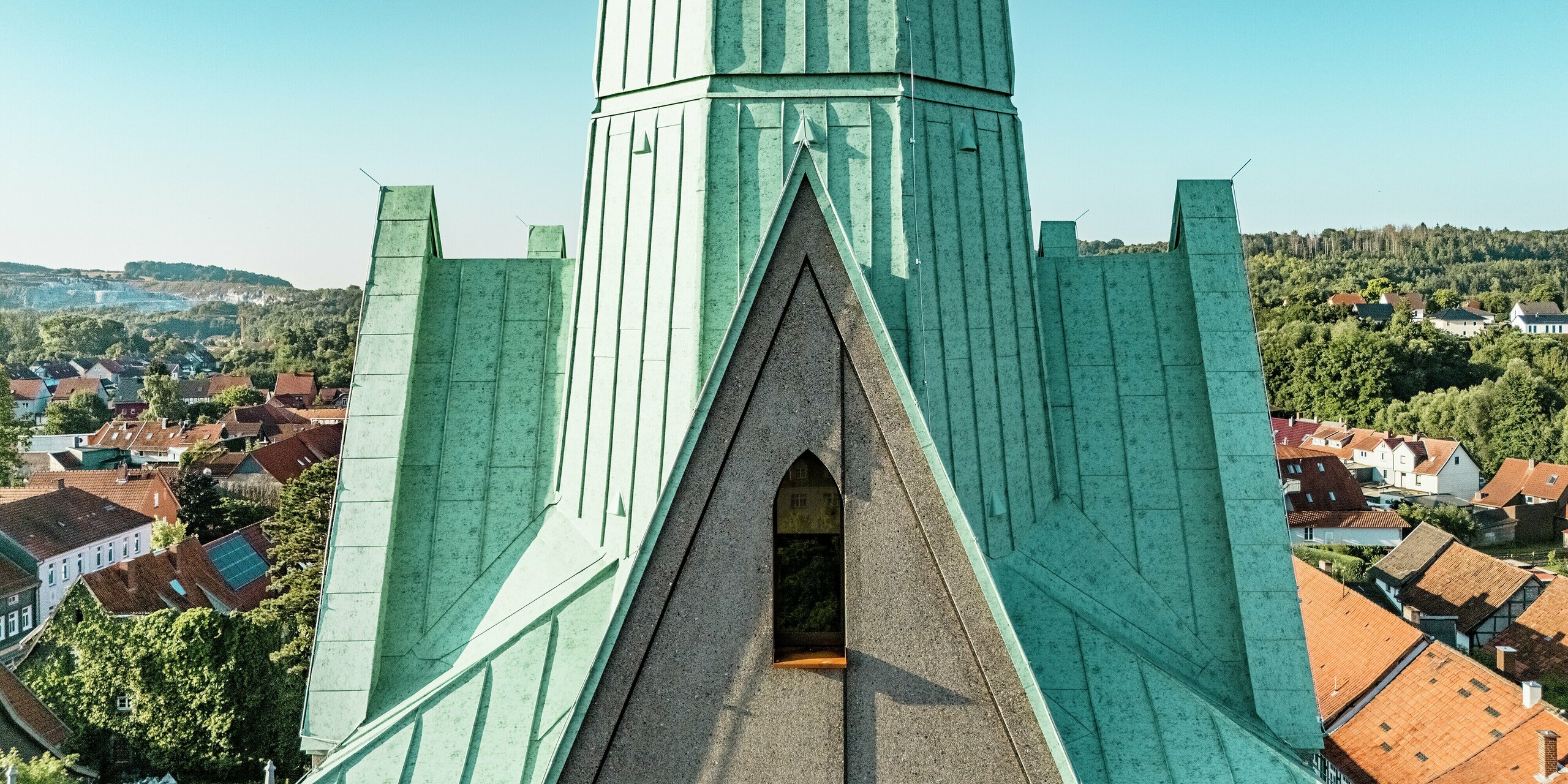 Gros plan majestueux sur les flèches nouvellement érigées de l'église Saint-Jean d'Ellrich, revêtues de PREFALZ P.10 vert de gris. Les joints debout, remarquables et réalisés en aluminium robuste, créent des accents architecturaux et s'harmonisent parfaitement avec l'environnement. PREFALZ séduit par sa durabilité, sa conception sans entretien et son esthétique élégante.