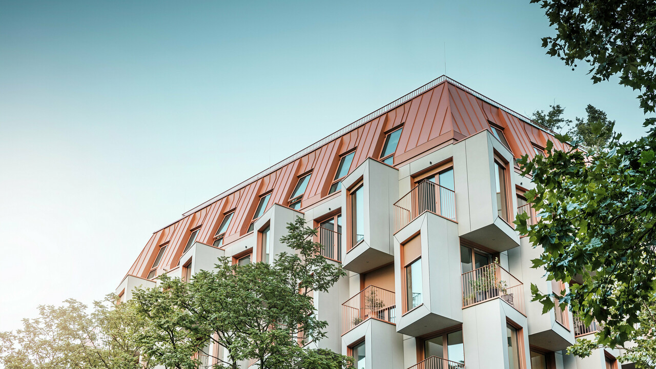 Architecture résidentielle moderne dans le projet Van B à Munich avec une façade en baie vitrée innovante et un toit en aluminium PREFALZ remarquable dans la couleur spéciale IGP Orange HDP de PREFA. Le matériau de toiture de haute qualité impressionne par son extrême durabilité, sa grande résistance et sa solidité des couleurs. En combinaison avec la conception cubique de la façade et les grandes surfaces vitrées, une image globale harmonieuse est créée qui combine fonctionnalité, design et durabilité au plus haut niveau - idéal pour la vie urbaine.