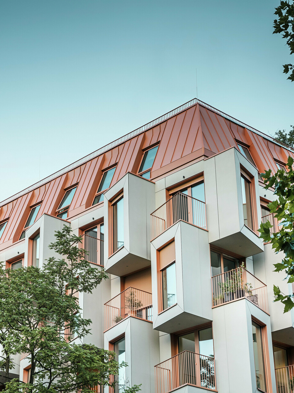 Architecture résidentielle moderne dans le projet Van B à Munich avec une façade en baie vitrée innovante et un toit en aluminium PREFALZ remarquable dans la couleur spéciale IGP Orange HDP de PREFA. Le matériau de toiture de haute qualité impressionne par son extrême durabilité, sa grande résistance et sa solidité des couleurs. En combinaison avec la conception cubique de la façade et les grandes surfaces vitrées, une image globale harmonieuse est créée qui combine fonctionnalité, design et durabilité au plus haut niveau - idéal pour la vie urbaine.