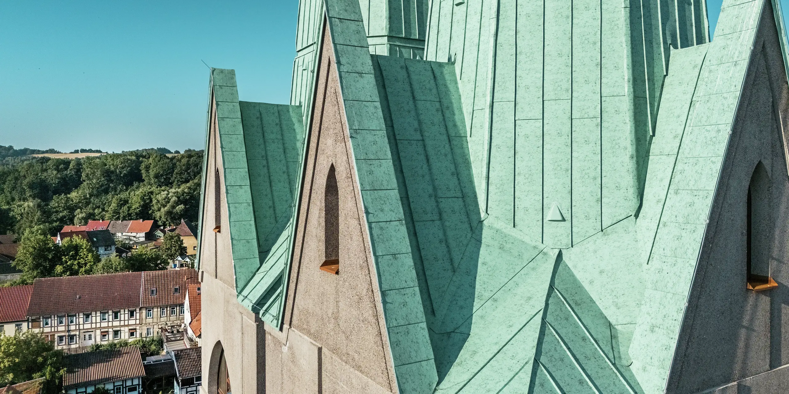 Détail du clocher nouvellement construit du Centre Touristique d'Ellrich : les joints précis réalisés en aluminium PREFALZ couleur Vert de gris P.10 attirent immédiatement le regard. La surface scintille au soleil et souligne la réinterprétation moderne de l'architecture historique. Robuste, durable et nécessitant peu d'entretien, le matériau PREFALZ, grâce à sa grande flexibilité de mise en œuvre, est parfaitement adapté aux toitures aux géométries complexes.