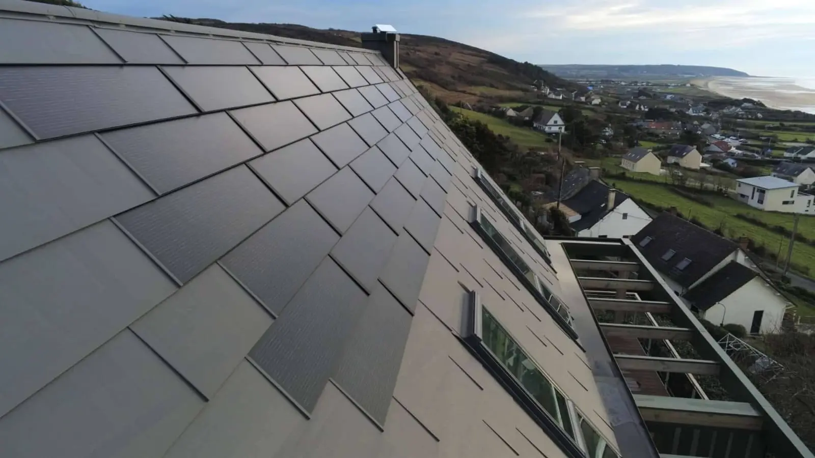 Zoom sur les tuiles solaires PREFA, teinte P.10 gris sombre, que l'entreprise Planque Couverture a utilisé pour rénover la toiture de cette maison individuelle. 
