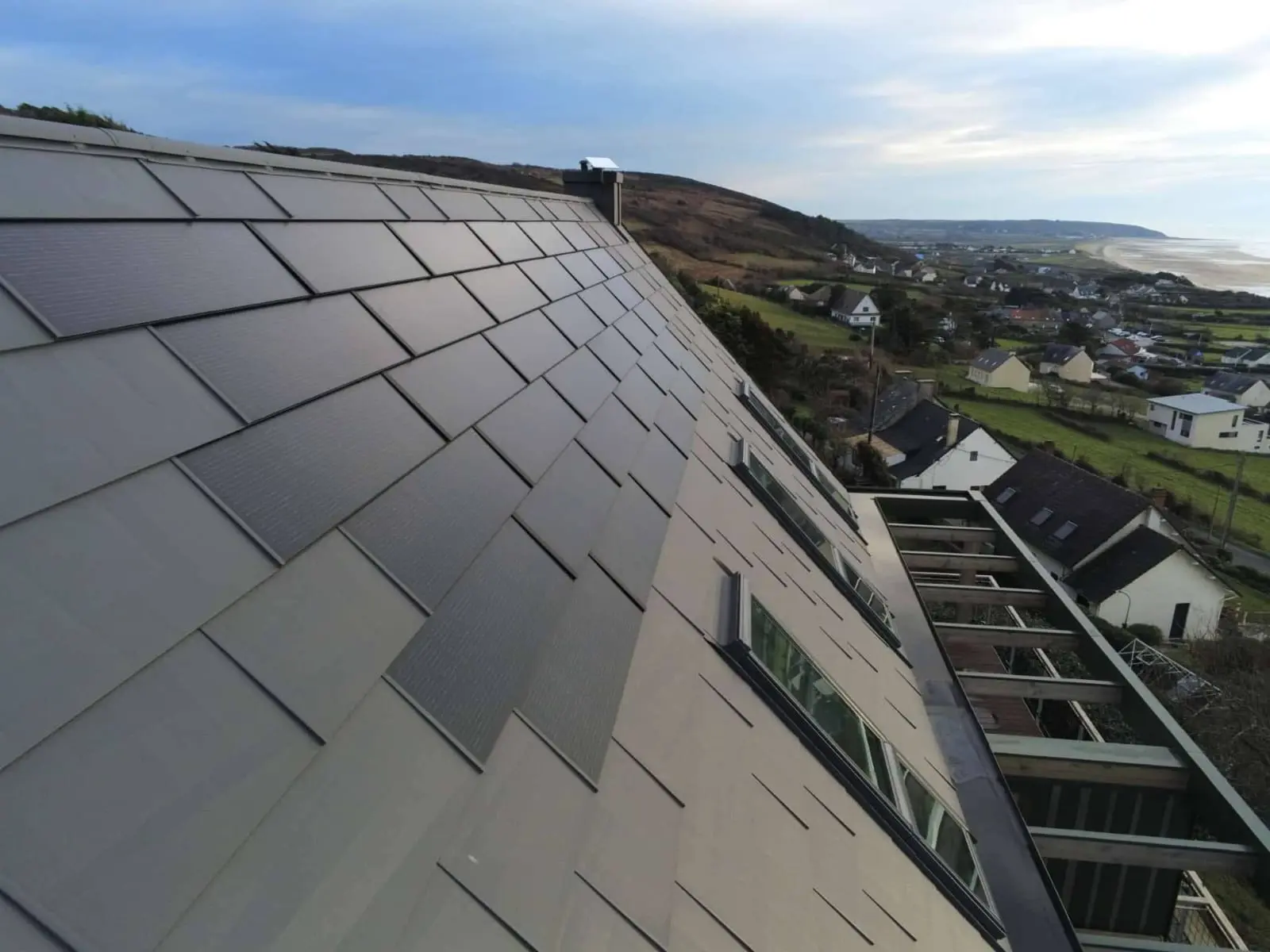 Zoom sur les tuiles solaires PREFA, teinte P.10 gris sombre, que l'entreprise Planque Couverture a utilisé pour rénover la toiture de cette maison individuelle. 