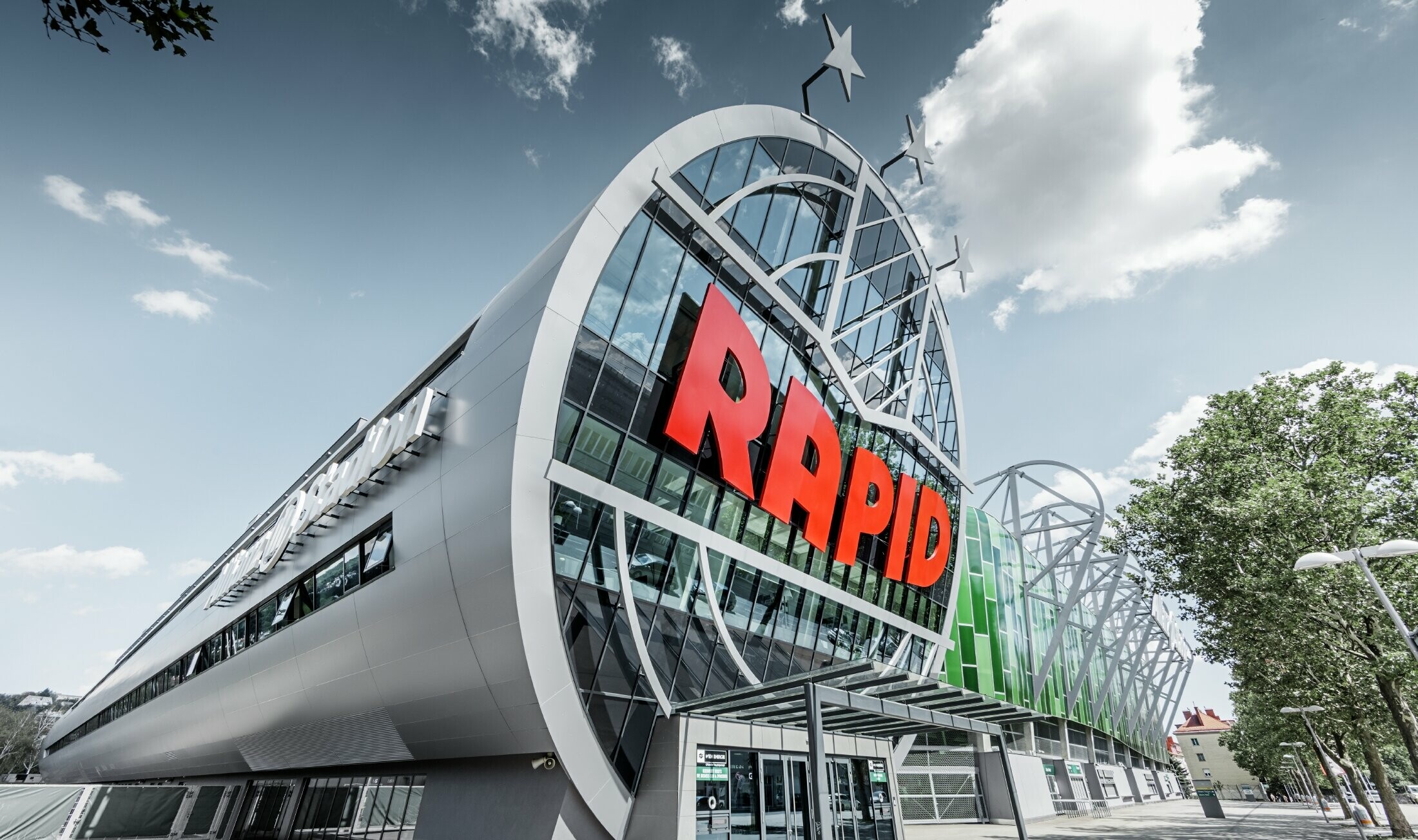 L’entrée de l’Allianz Stadion avec le grand logo du SK Rapid de Vienne ; le tube avec la grande façade vitrée est recouvert du panneau composite en aluminium PREFA couleur argent métallisé.