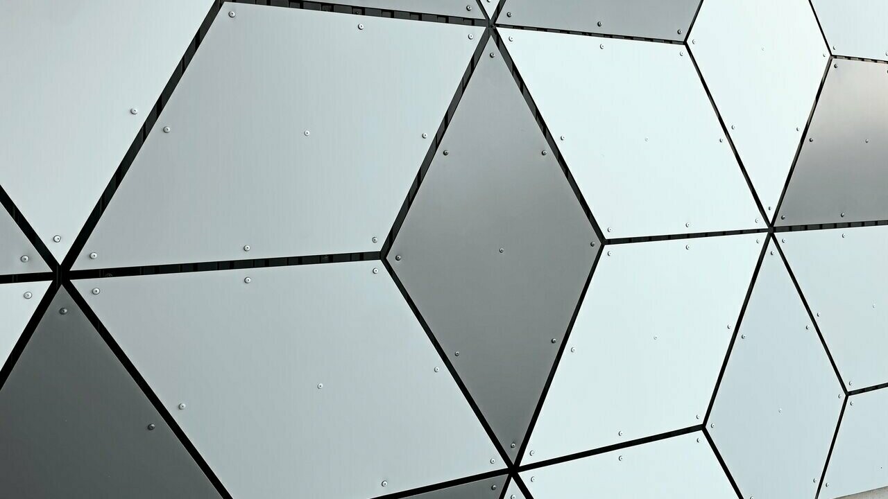 Focus sur les motifs losangés formés par les panneaux composites en aluminium PREFABOND choisis en trois couleurs différentes : blanc Prefa, blanc pur et argent fumé. Le tout sur les façades des stations du nouveau téléphérique Le Jandri implanté à Les 2 Alpes.