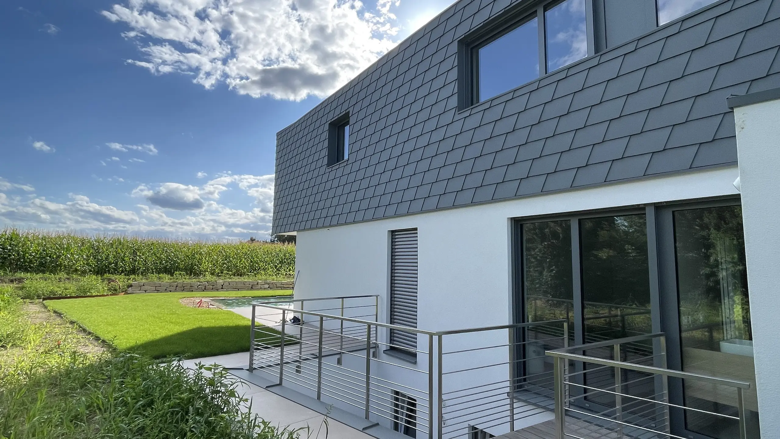 Vue latérale de cette maison contemporaine dont la façade est couverte de bardeaux en aluminium PREFA dans la teinte P.10 gris souris