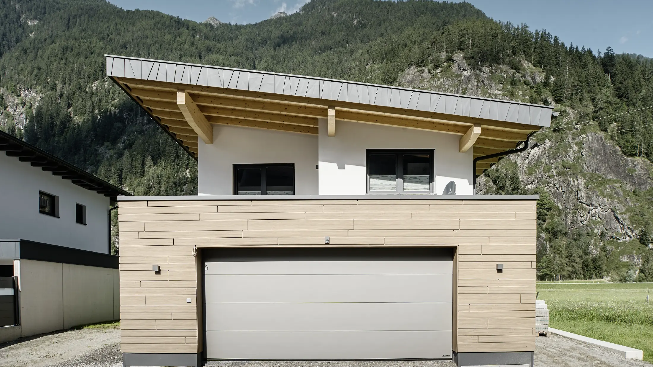 Nouvelle construction moderne avec toit en appentis et bardage individuel, garage avec toit plat et façade en aluminium noyer foncé de PREFA. Les Sidings ont été posés horizontalement et dans différentes largeurs utiles.