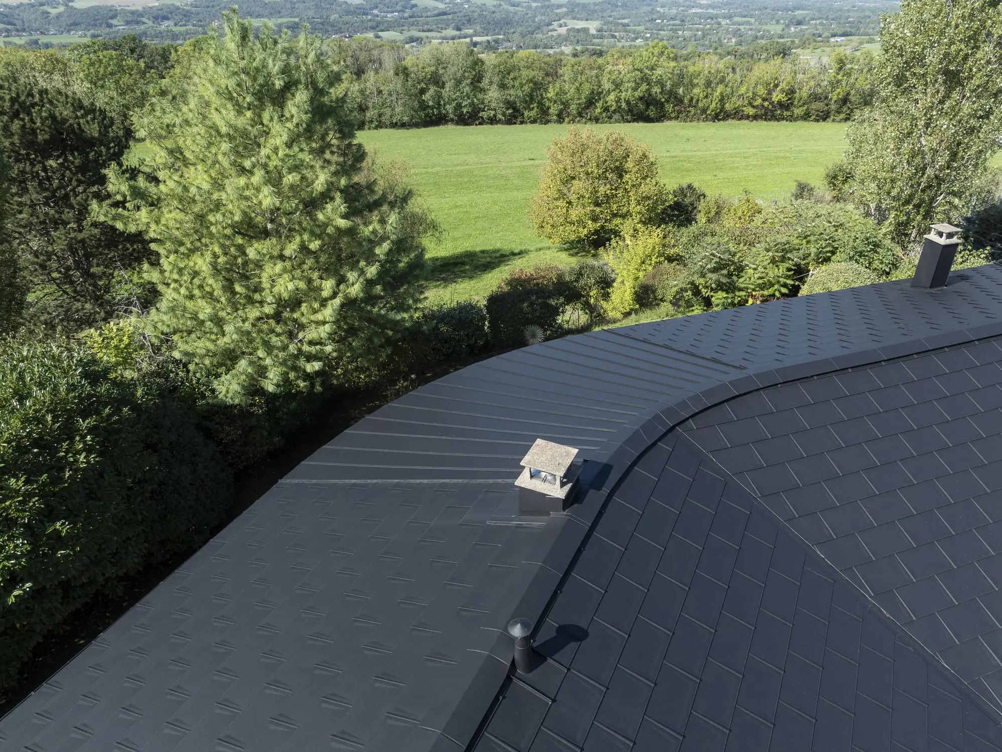 Photo du haut du toit où on distingue clairement le côté courbé et arrondi de la toiture. Un défi technique relevé grâce aux produits PREFA et à la flexibilité de l'aluminium.