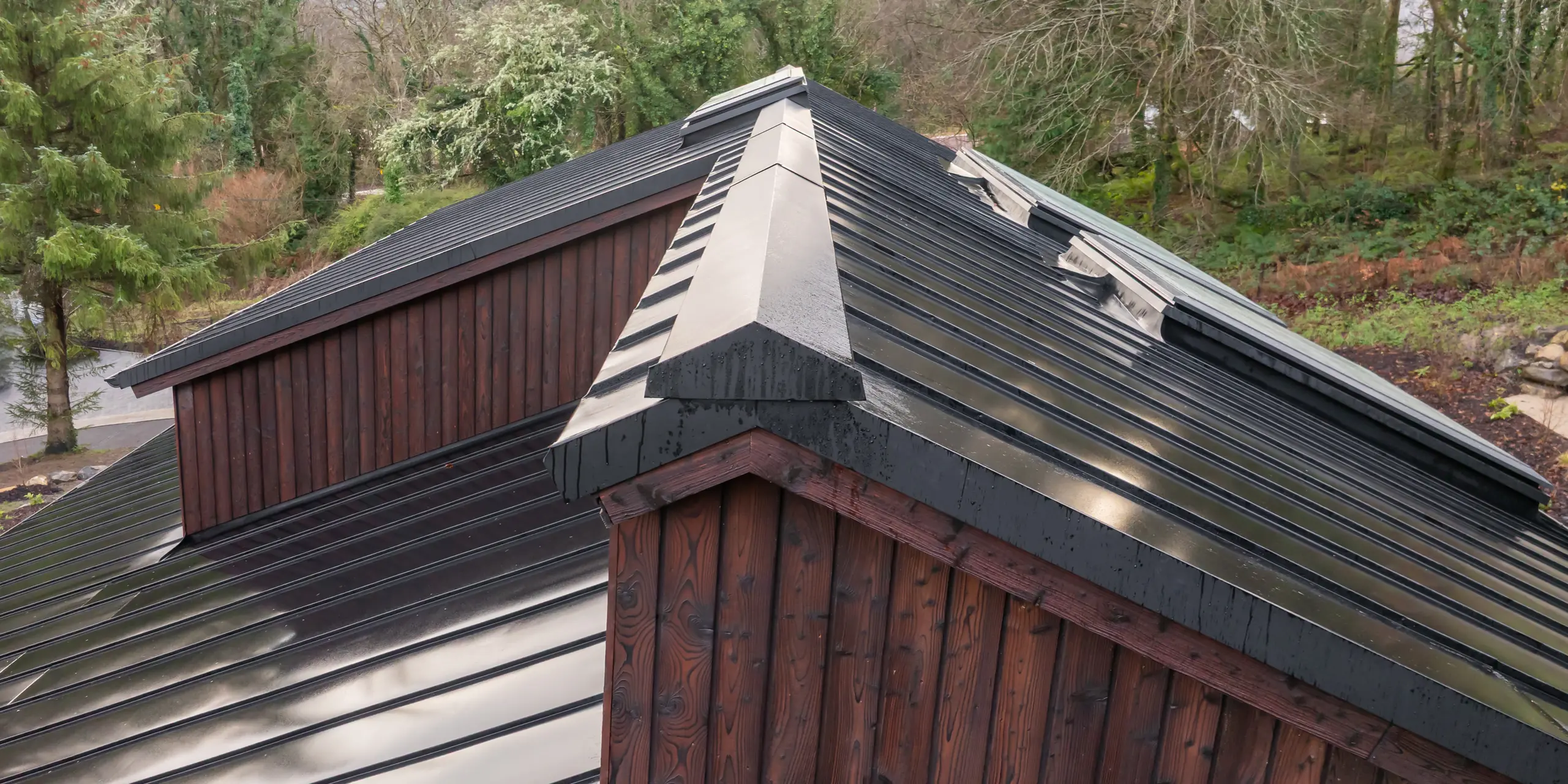  505 Vue dynamique de la toiture de la Maison Holywell à Sligo : la toiture en aluminium PREFALZ P.10 Noir épouse avec précision les pentes et les lignes de faîtage. Les joints verticaux reflètent la lumière et soulignent la géométrie architecturale. Les détails apparents, tels que les arêtiers et les faîtières, témoignent du savoir-faire artisanal. La toiture PREFA impressionne par sa durabilité, sa résistance à la corrosion et sa protection fiable par tous les temps.