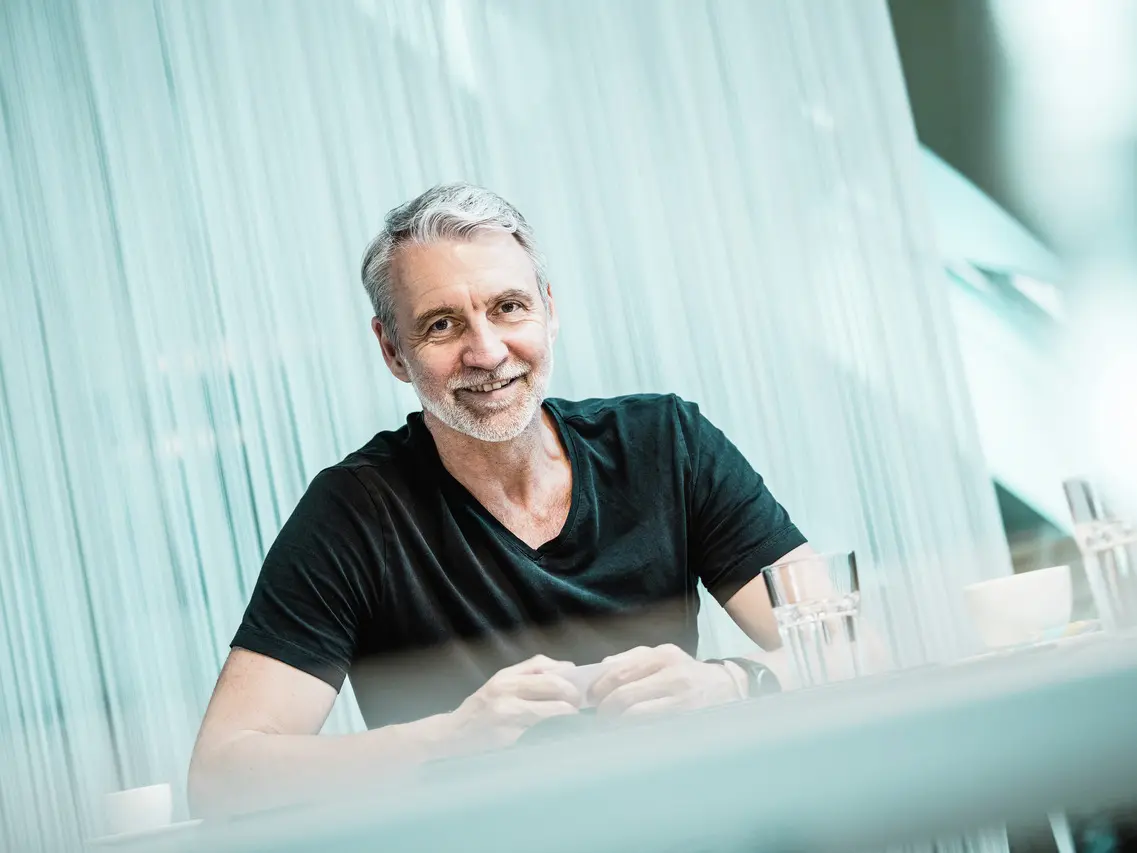 Portrait de l'architecte Oliver Kupfner, souriant et détendu, assis à une table