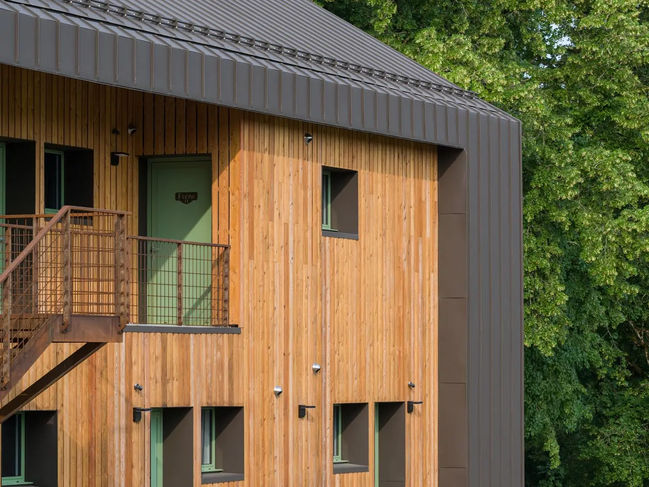 Vue latérale de l'hôtel en tilleul, on voit le mélange de bois et d'aluminium 