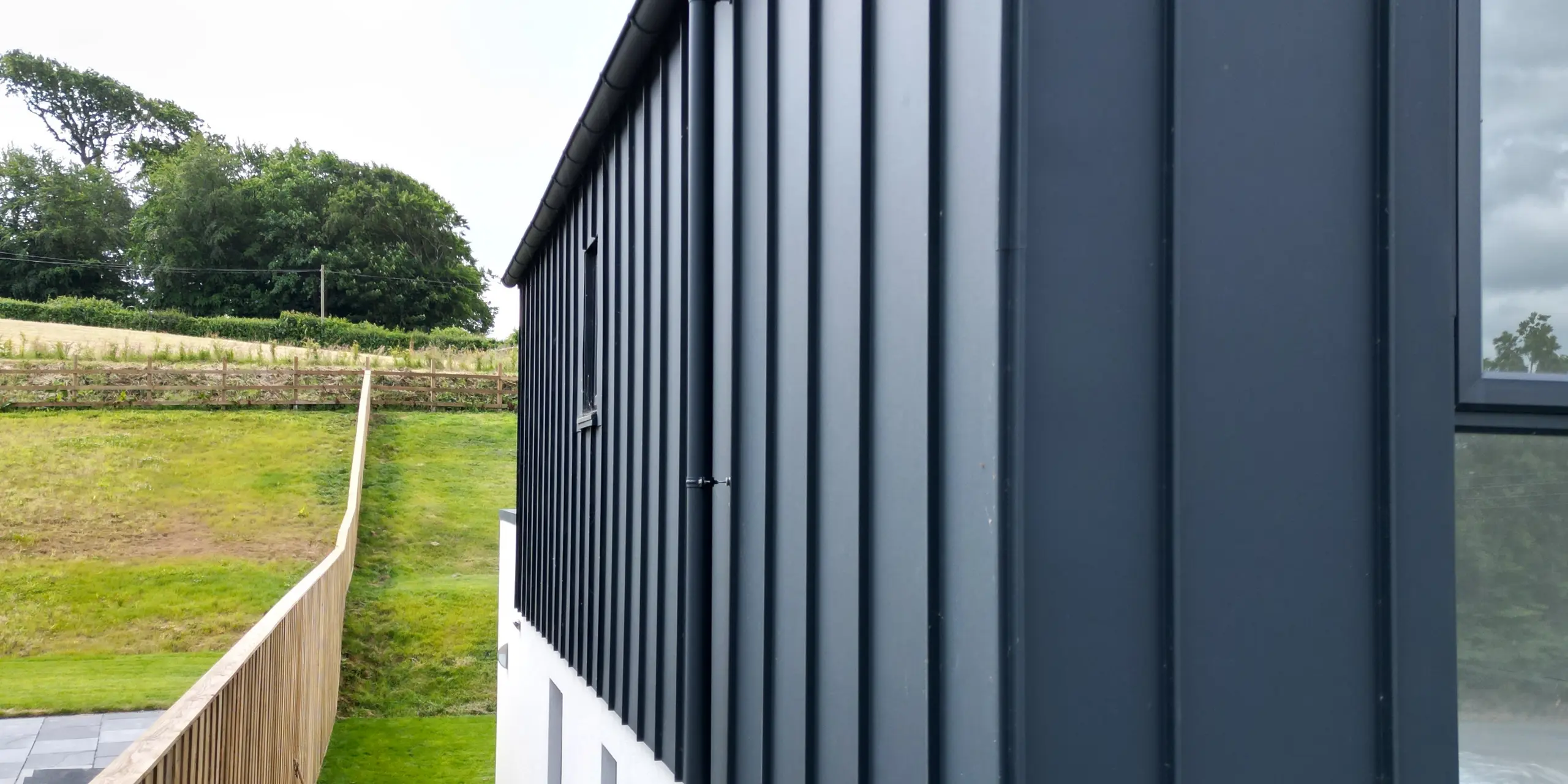 Gros plan de la façade PREFALZ en P.10 anthracite, qui met en valeur l'aluminium de haute qualité et la finition précise de la toiture à joint debout. Les lignes claires et la surface résistante aux UV font de cette façade un accroche-regard moderne.