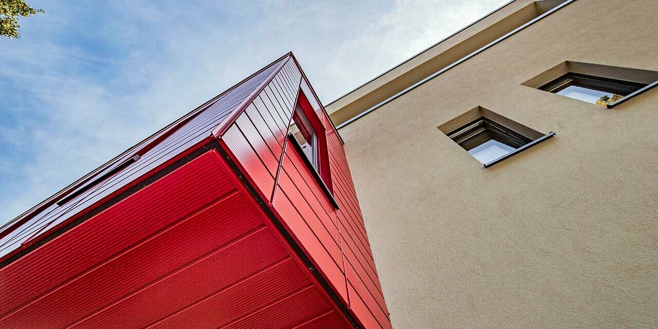 Oriel avec Sidings PREFA finition lignée couleur rouge rubis sur une maison individuelle moderne à Wernigerode, la sous-face de l’extension en porte-à-faux est photographiée ici.