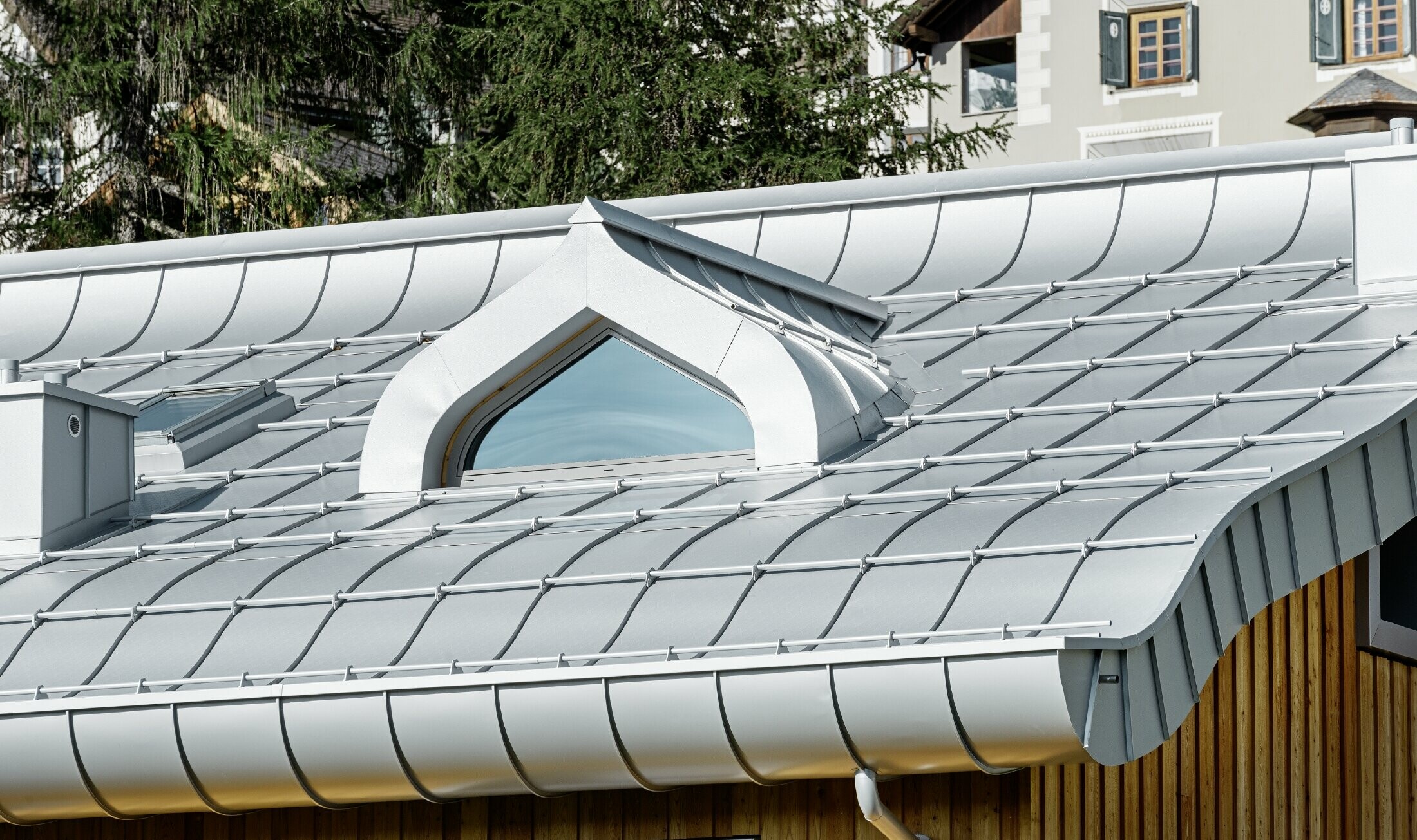 Complexe résidentiel de St. Moritz à la façade en bois — Toiture en aluminium PREFA de couleur argent métallisé avec avant-toit curviligne