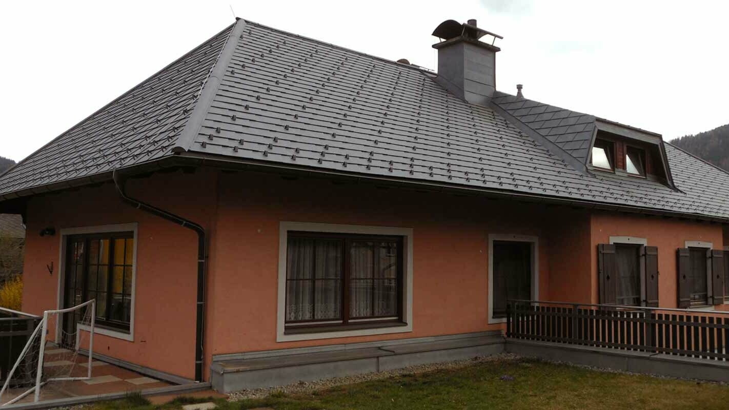 Rénovation de toiture d’une maison avec toit à croupes et lucarne en trapèze, à l’aide de bardeaux de toiture PREFA