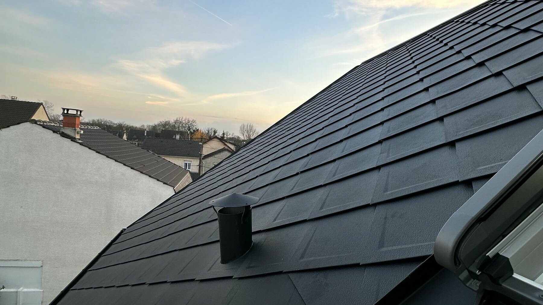 Prise de vue réalisée pendant les travaux avec un zoom sur le raccordement de la fenêtre de toit aux losanges PREFA. On aperçoit même une grue en arrière plan.