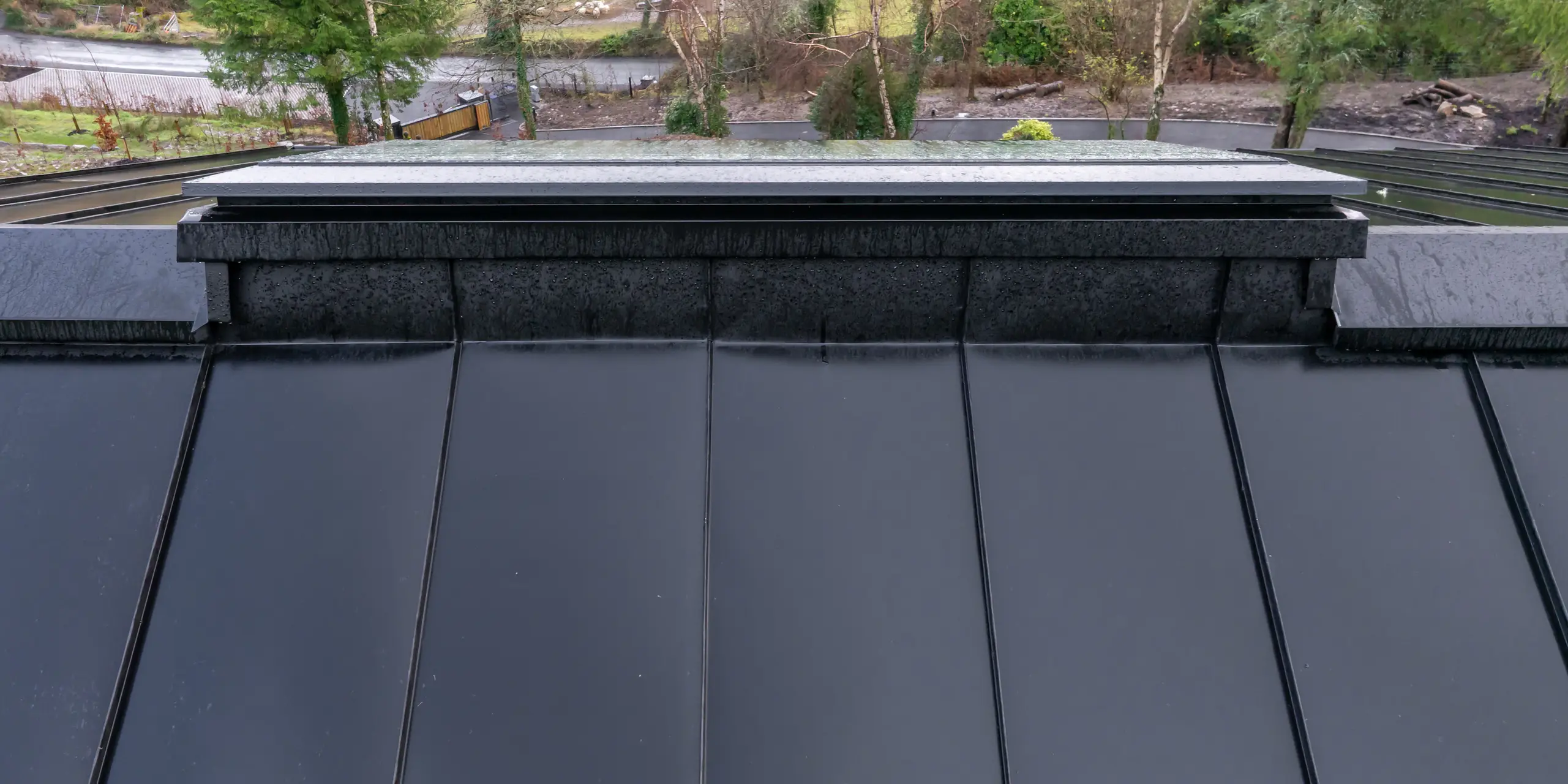 Une perspective saisissante le long du faîtage de la Maison Holywell à Sligo : les lignes précises de la toiture en aluminium PREFALZ P.10 Noir guident le regard, au-delà des joints debout réguliers et rythmés, vers le vaste paysage. La construction minutieuse du faîtage et la netteté des raccords témoignent d’une grande qualité d’exécution. La surface lisse permet une évacuation efficace des eaux pluviales et souligne les atouts de la toiture PREFA : durabilité, résistance à la corrosion et adaptation optimale aux conditions climatiques difficiles.