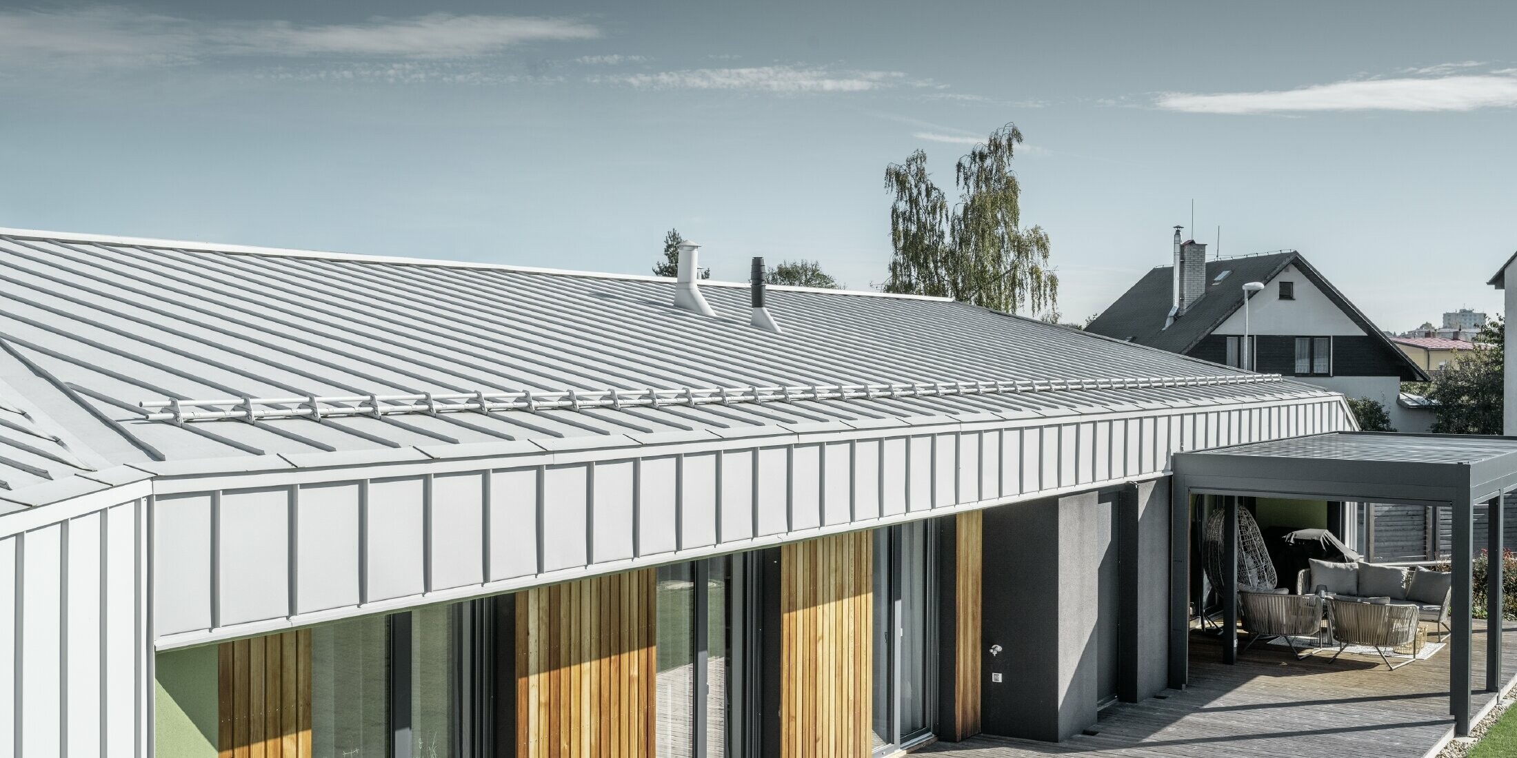 Bungalow avec toit et façade PREFALZ couleur blanc Prefa et terrasse en bois