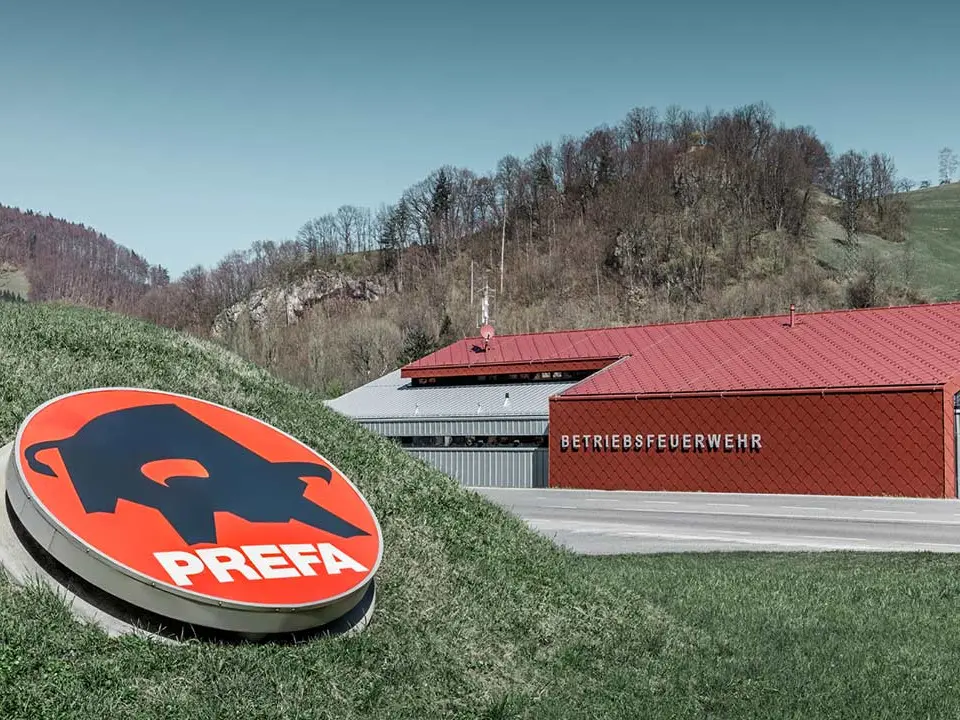 neue Betriebsfeuerwehr in Marktl, Lilienfeld, mit der roten Dach- und Wandraute 44x44 von PREFA mit dem PREFA Logo im Vordergrund, mit silbermetallic Alufassade am Seitenteil