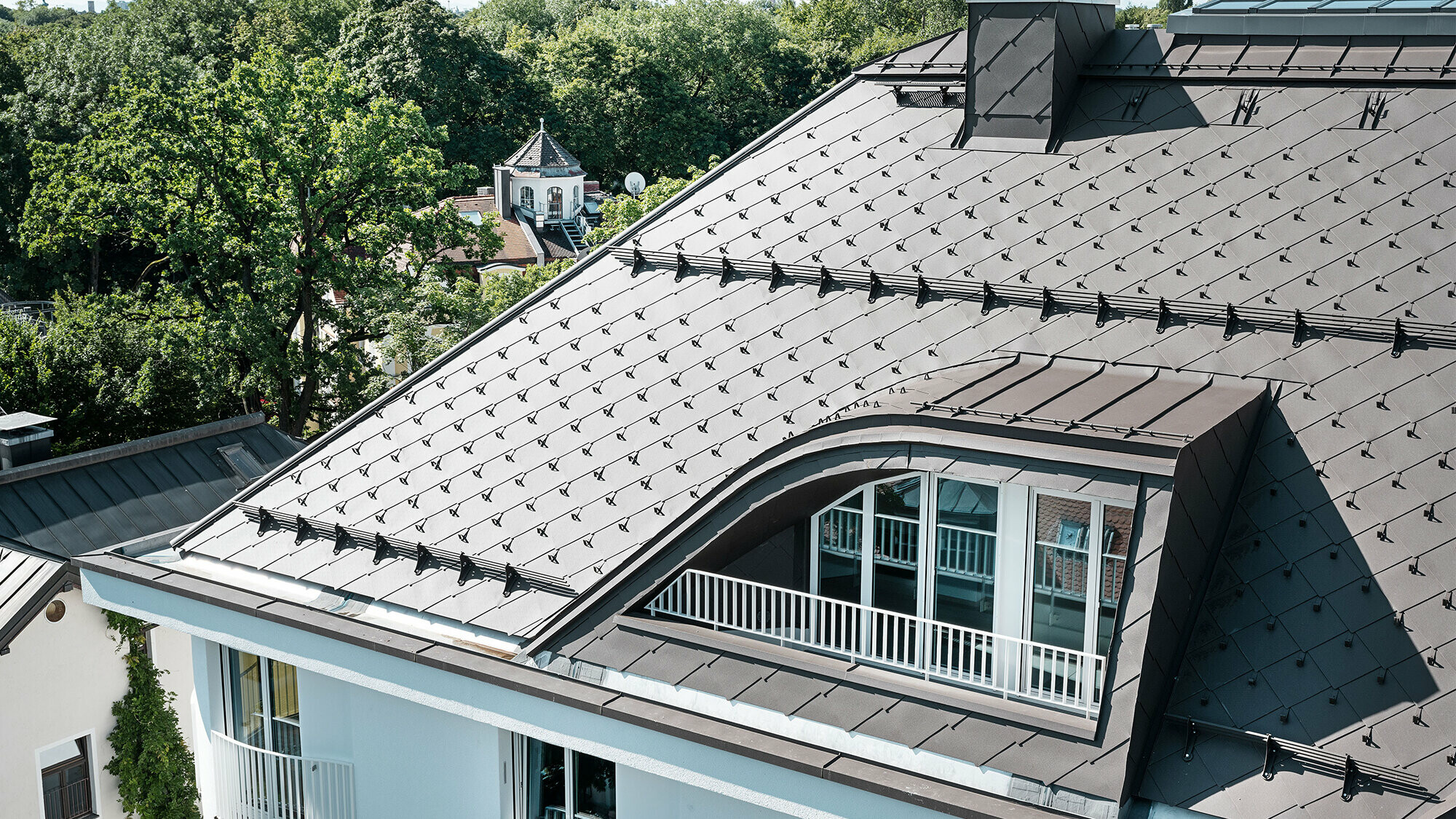 Immeuble résidentiel avec losange de toiture 44 × 44 de PREFA en brun avec arrêts neige et système pare-neige