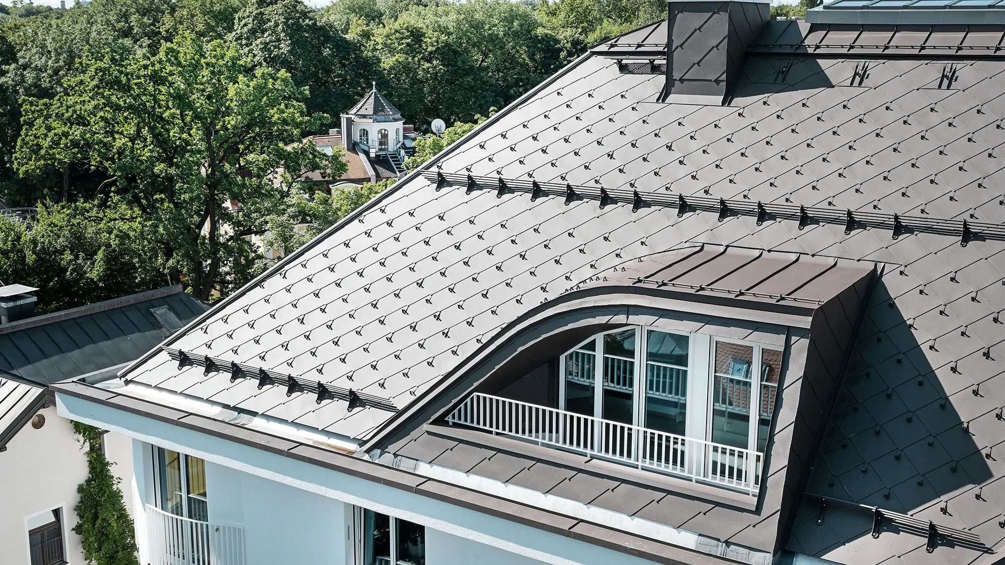 Immeuble résidentiel avec losange de toiture 44 × 44 de PREFA en brun avec arrêts neige et système pare-neige