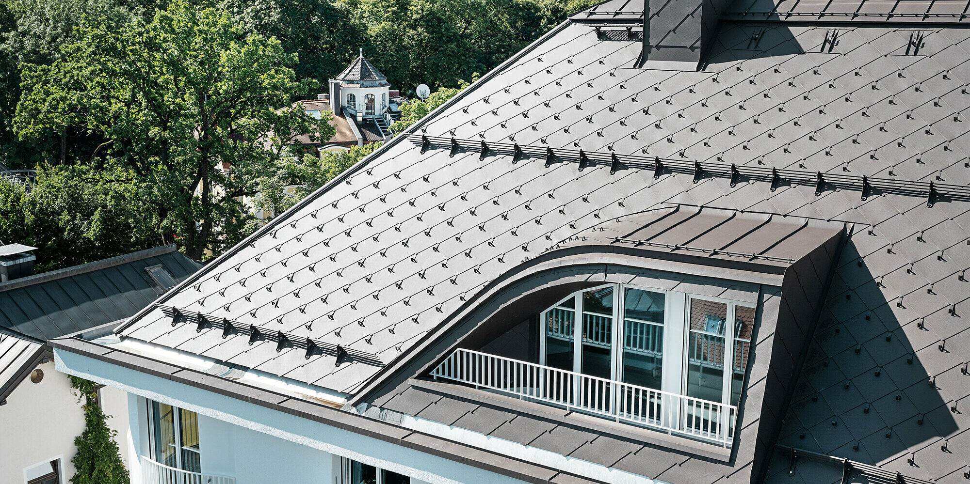 Immeuble résidentiel avec losange de toiture 44 × 44 de PREFA en brun avec arrêts neige et système pare-neige