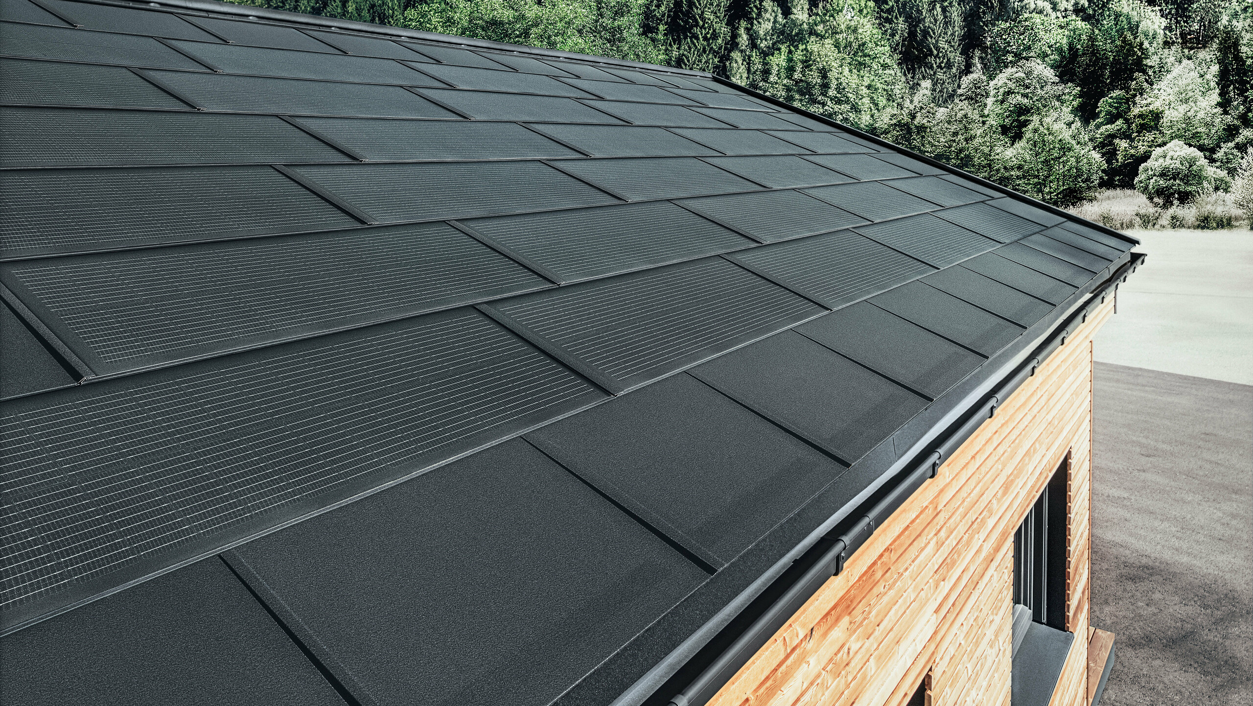 Tuile solaire PREFA grand format, combinée à la R.16 en noir, gouttière et façade en mélèze