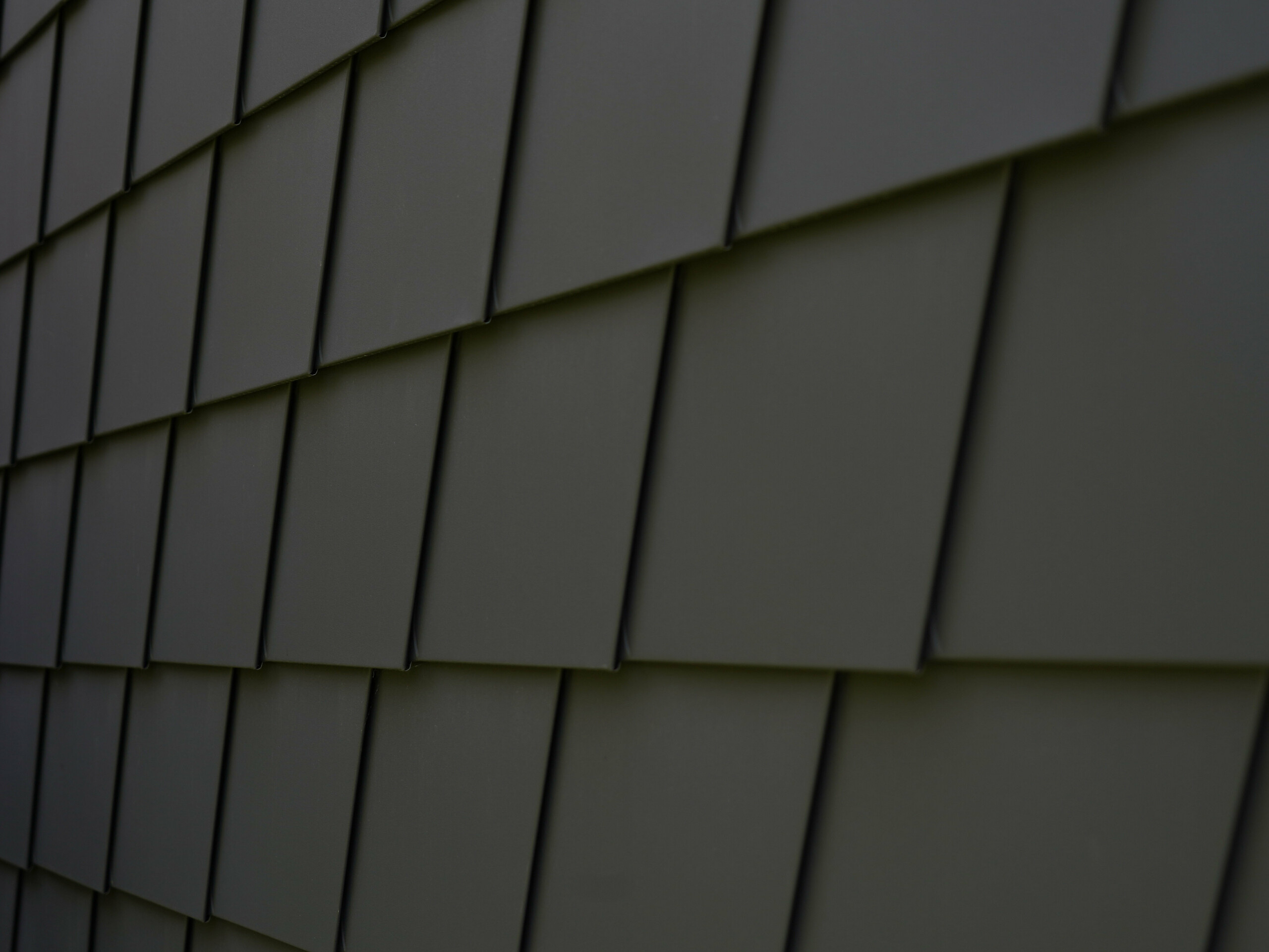 Prise de vue centrée sur l'arrière du bureau mobile où toute la façade est revêtue de bardeau en aluminium PREFA 