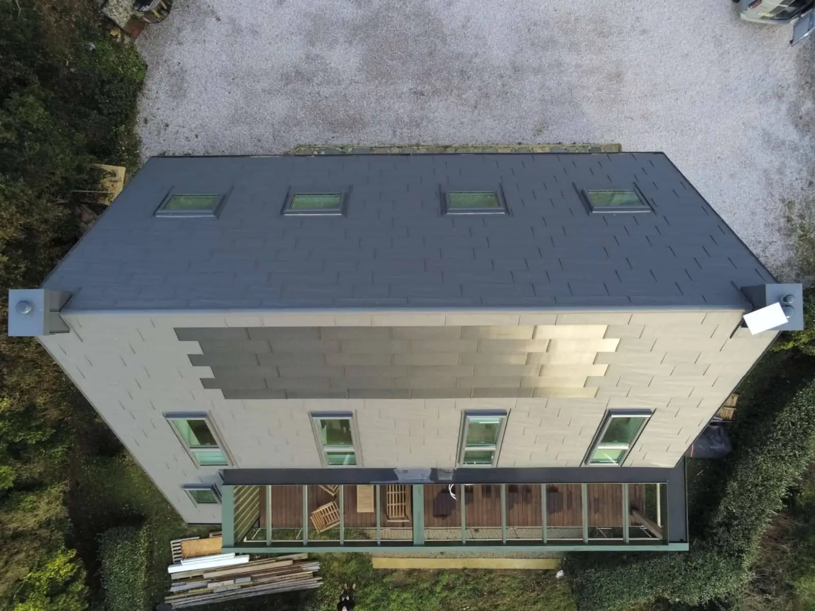 Prise de vue de haut de la toiture cette maison familiale située face à la mer, à Les Pieux. Elle a récemment été rénovée avec les produits de toiture PREFA : panneaux FX.12 et tuile solaire PREFA dans la teinte P.10 gris sombre.