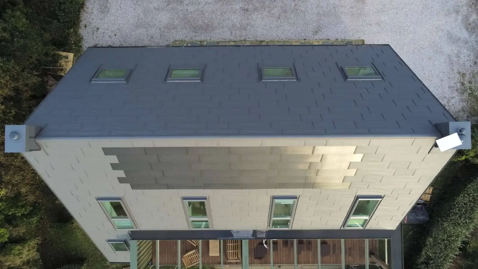 Prise de vue de haut de la toiture cette maison familiale située face à la mer, à Les Pieux. Elle a récemment été rénovée avec les produits de toiture PREFA : panneaux FX.12 et tuile solaire PREFA dans la teinte P.10 gris sombre.