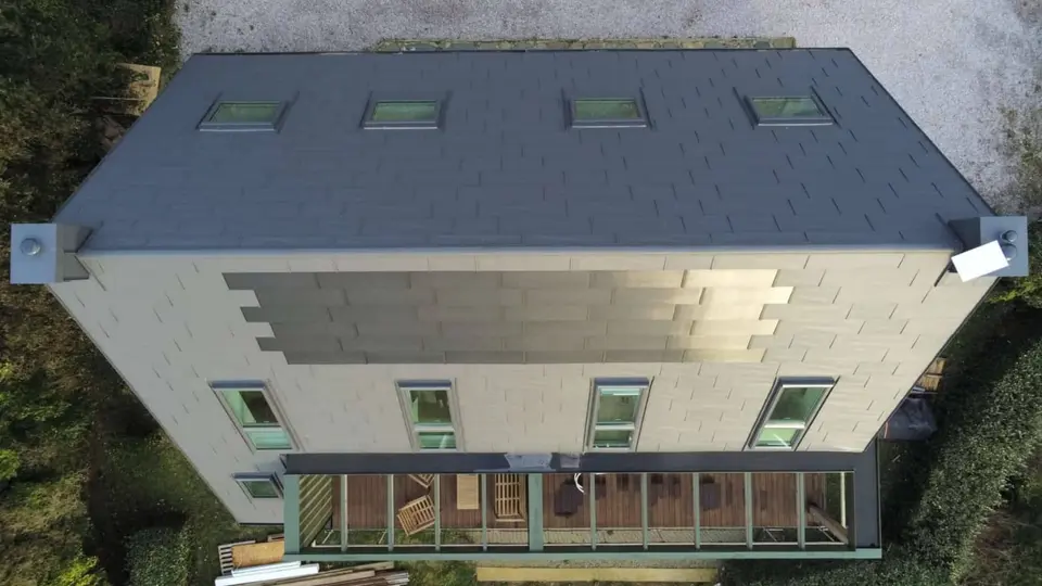 Prise de vue de haut de la toiture cette maison familiale située face à la mer, à Les Pieux. Elle a récemment été rénovée avec les produits de toiture PREFA : panneaux FX.12 et tuile solaire PREFA dans la teinte P.10 gris sombre.