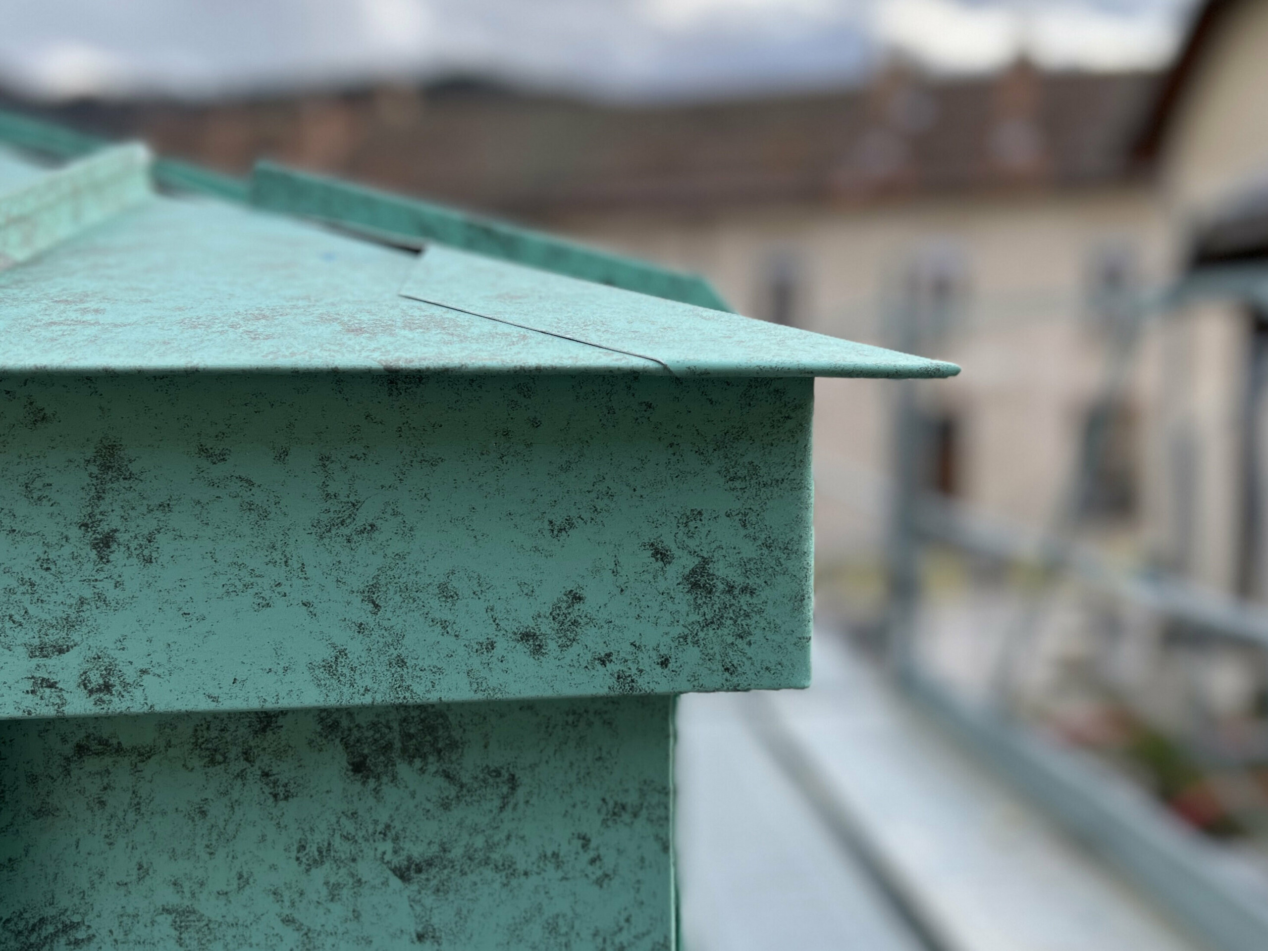 Zoom sur le détail de raccord entre la toiture et la façade, tous deux réalisés en joint debout en aluminium PREFA