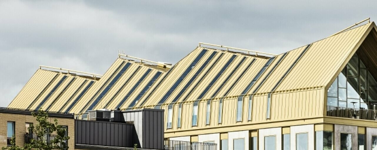 Vue latérale du bâtiment à Malmö, revêtu grâce au système de toiture PREALZ dans la teinte spéciale Jaisalmer Gold.