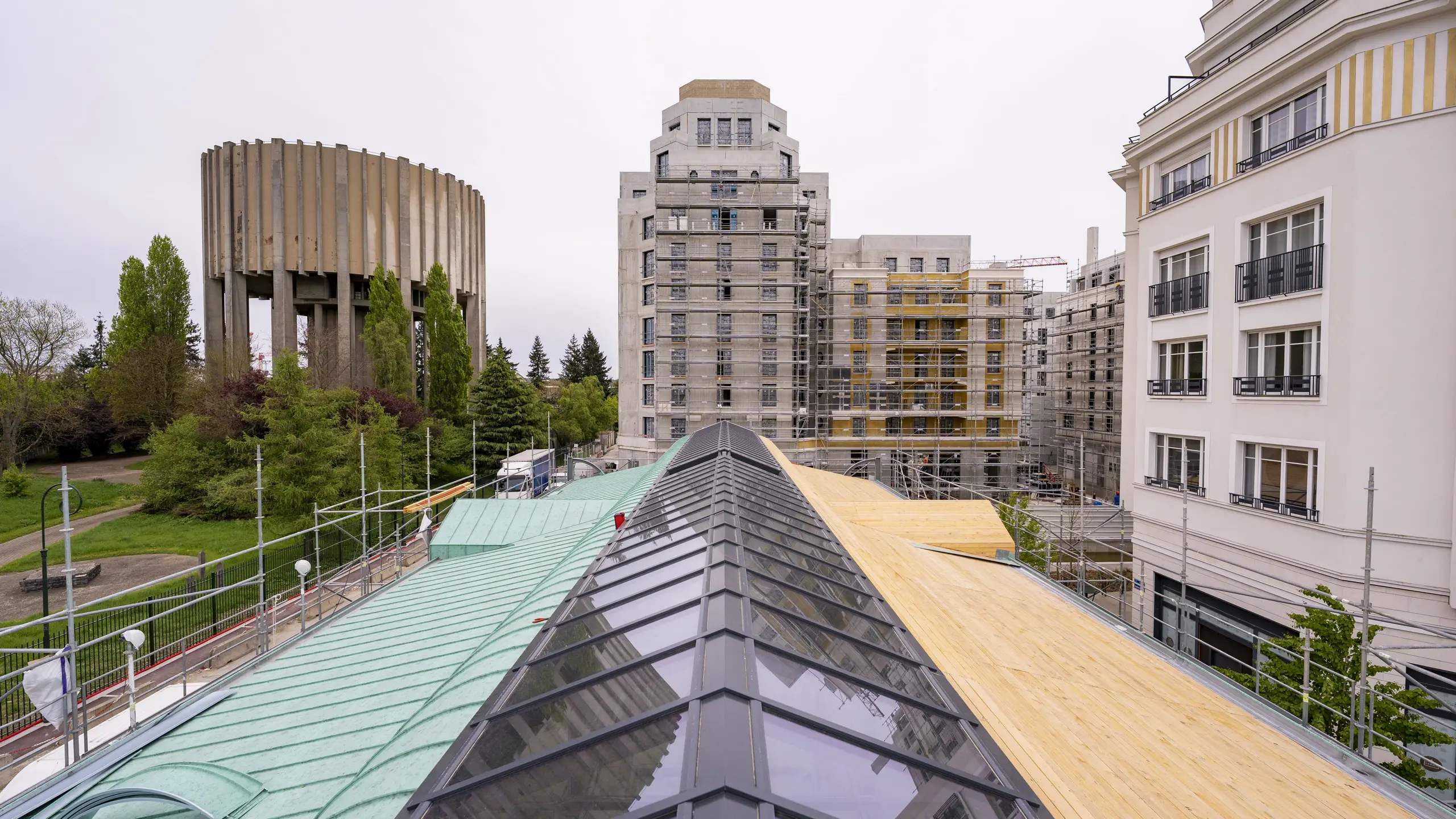 Photo prise de hauteur où l'on voit une partie de la toiture de la Halle de Clamart recouverte de joint debout PREFA dans la teinte P.10 vert-de-gris et l'autre moitié en attente.