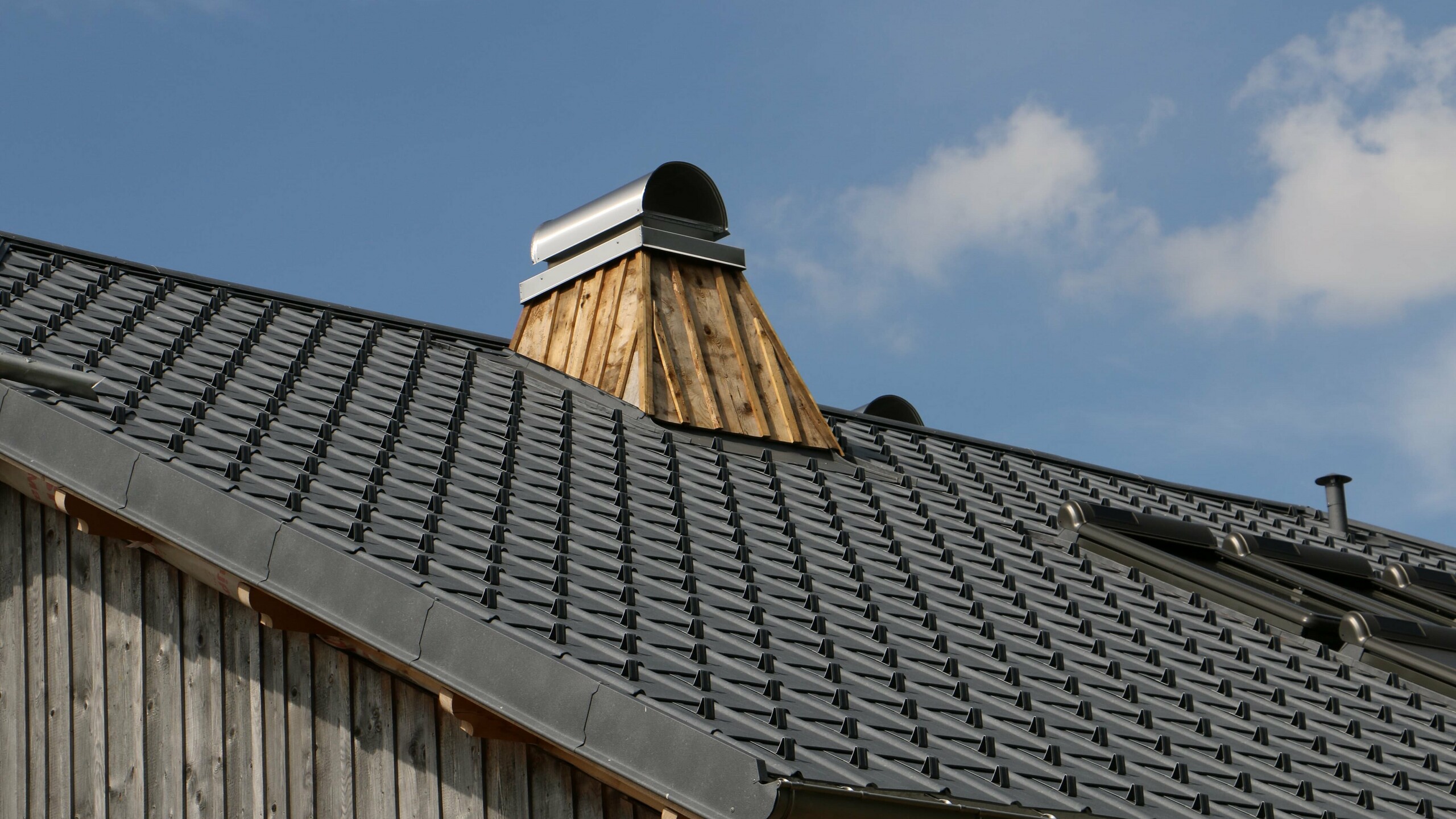Prise de vue de détail de cheminée sur cette toiture rénovée en tuile prefa