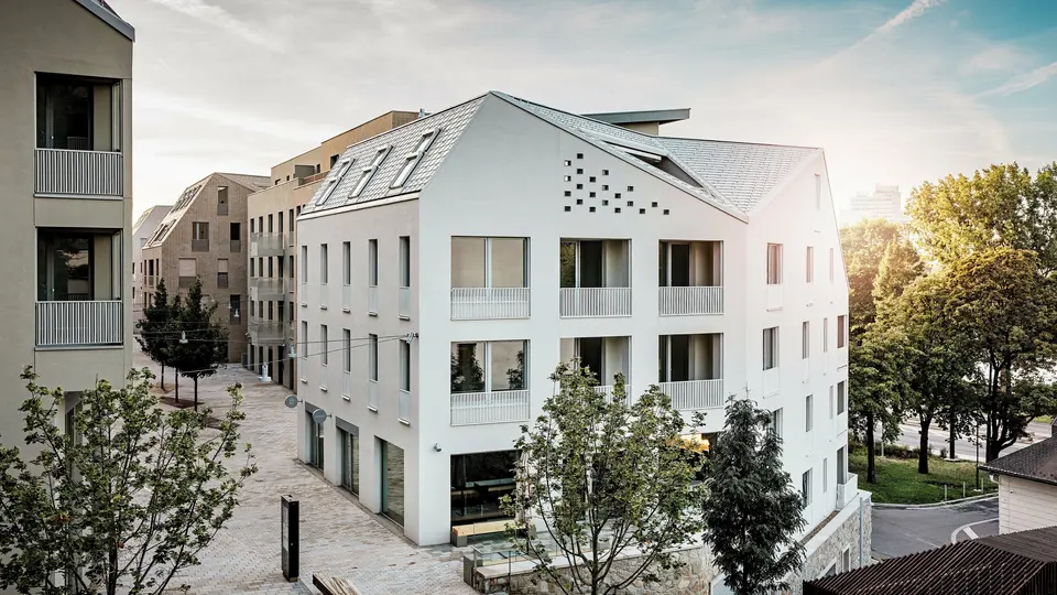 Le quartier résidentiel moderne de Vydrica à Bratislava se distingue par un style architectural affirmé et un paysage urbain paisible. Les toits à pignons à forte pente, agrémentés de remarquables puits de lumière, sont recouverts de tuiles en aluminium PREFA, coloris P.10 Blanc Prefa, Bronze et P.10 Brun Sable, créant ainsi un point focal élégant baigné de soleil. La précision des lignes et l'homogénéité des surfaces soulignent la grande qualité de la conception. L'aluminium PREFA est reconnu pour sa durabilité, sa légèreté et son excellente résistance aux intempéries – des atouts idéaux pour les toitures aux formes complexes et pour une enveloppe de bâtiment durable et nécessitant peu d'entretien.