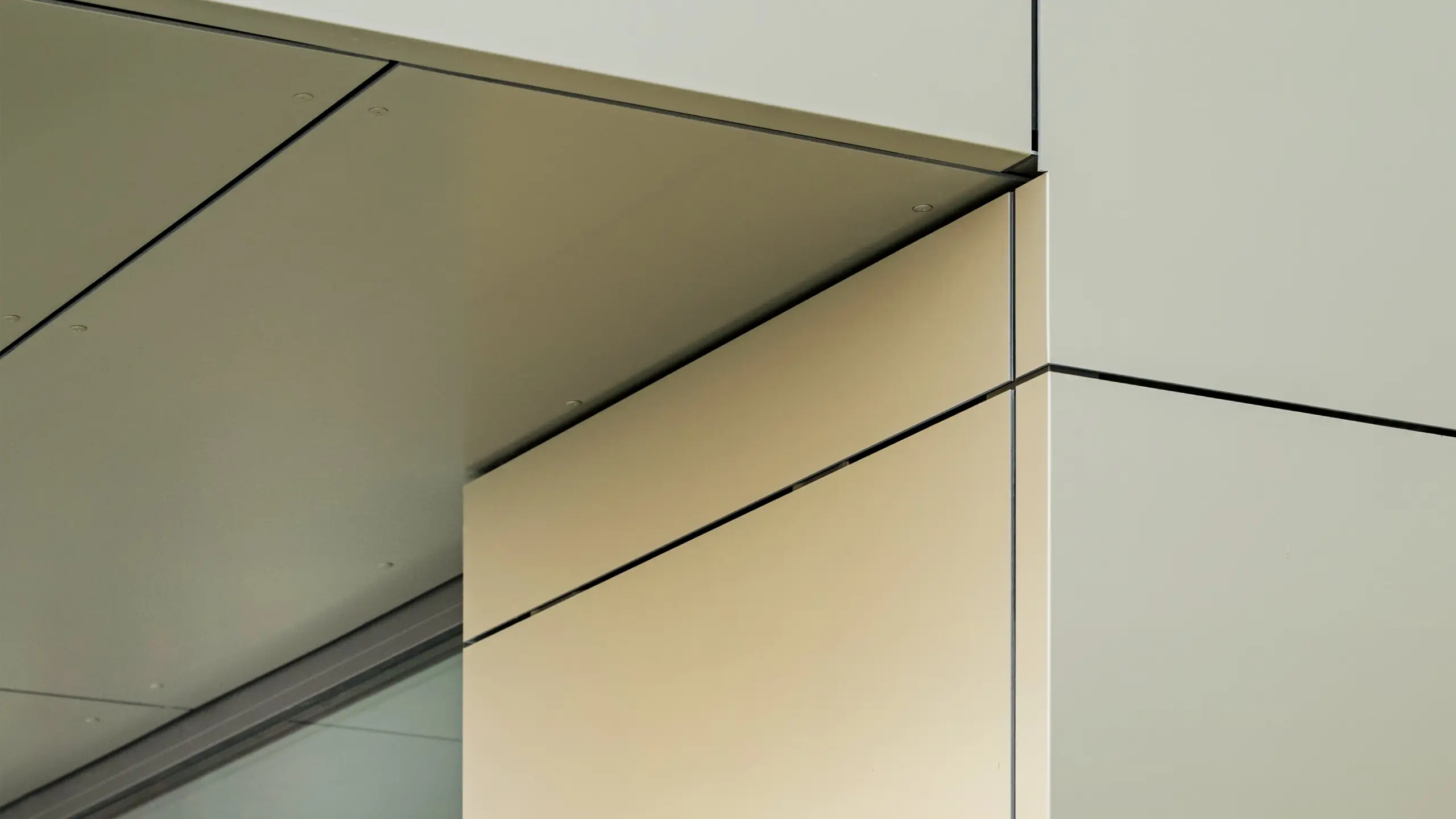 Détail de la façade de la mairie d'Alzenau, qui montre la précision des arêtes et des transitions des panneaux composites en aluminium PREFA, ici dans la couleur bronze. Les panneaux sont parfaitement assemblés, créant ainsi des lignes claires et modernes. La brillance métallique des panneaux est soulignée par les lignes fines des joints et les détails minimalistes de l'architecture, ce qui confère à la façade un aspect élégant et contemporain.