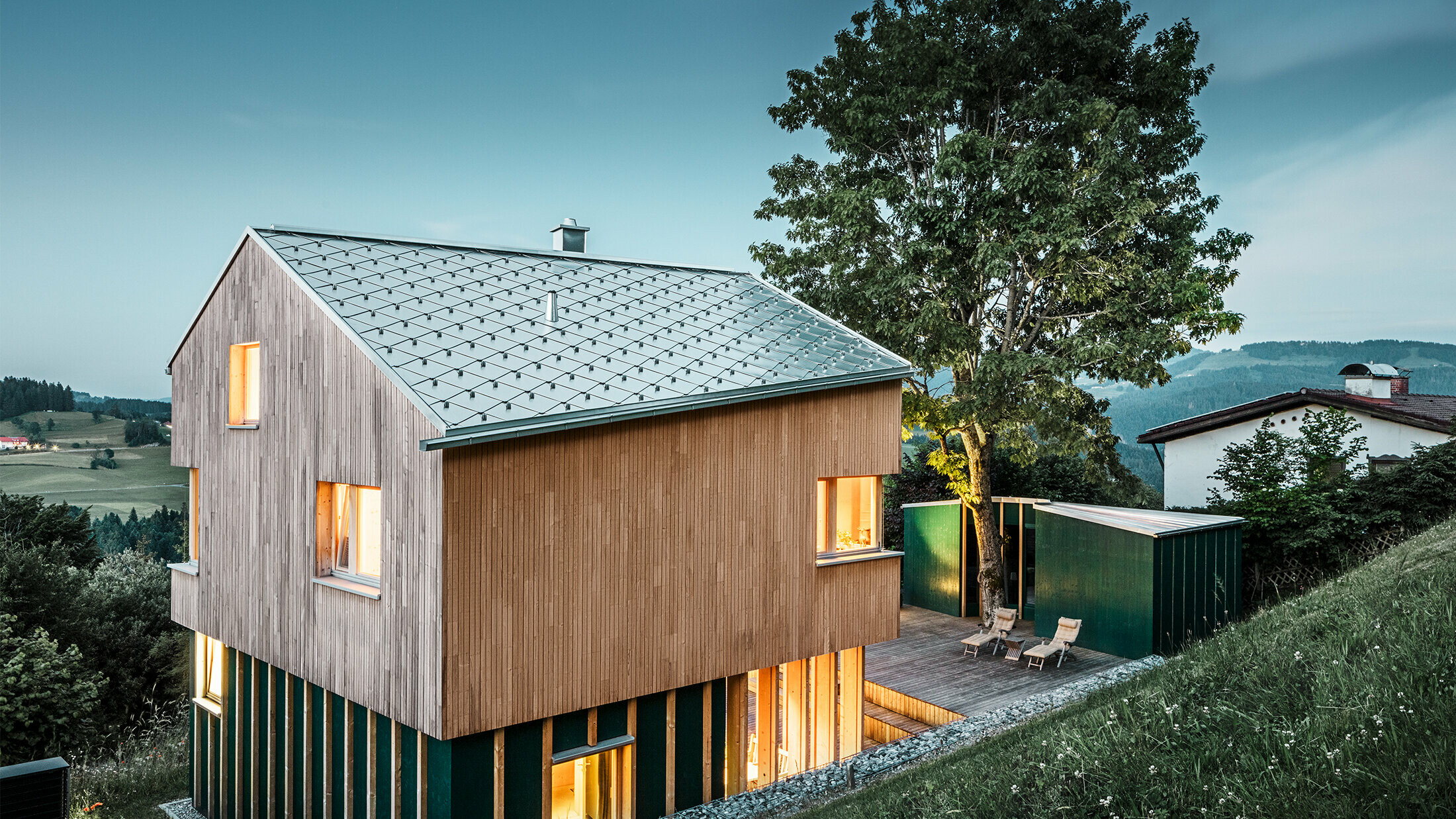 Nouvelle maison individuelle avec façade en bois et toiture PREFA en aluminium naturel en forme de losanges