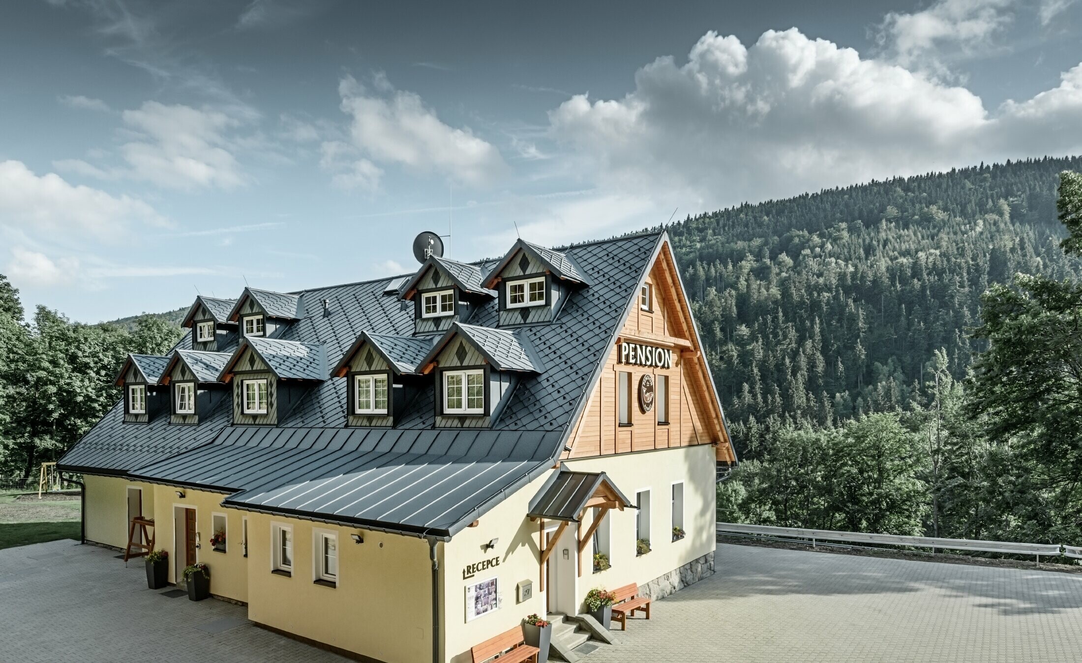 Maison de retraite en République tchèque, avec toit fortement incliné et nombreuses lucarnes, avec un toit en aluminium de PREFA, couverture en losanges avec protection contre le glissement de la neige