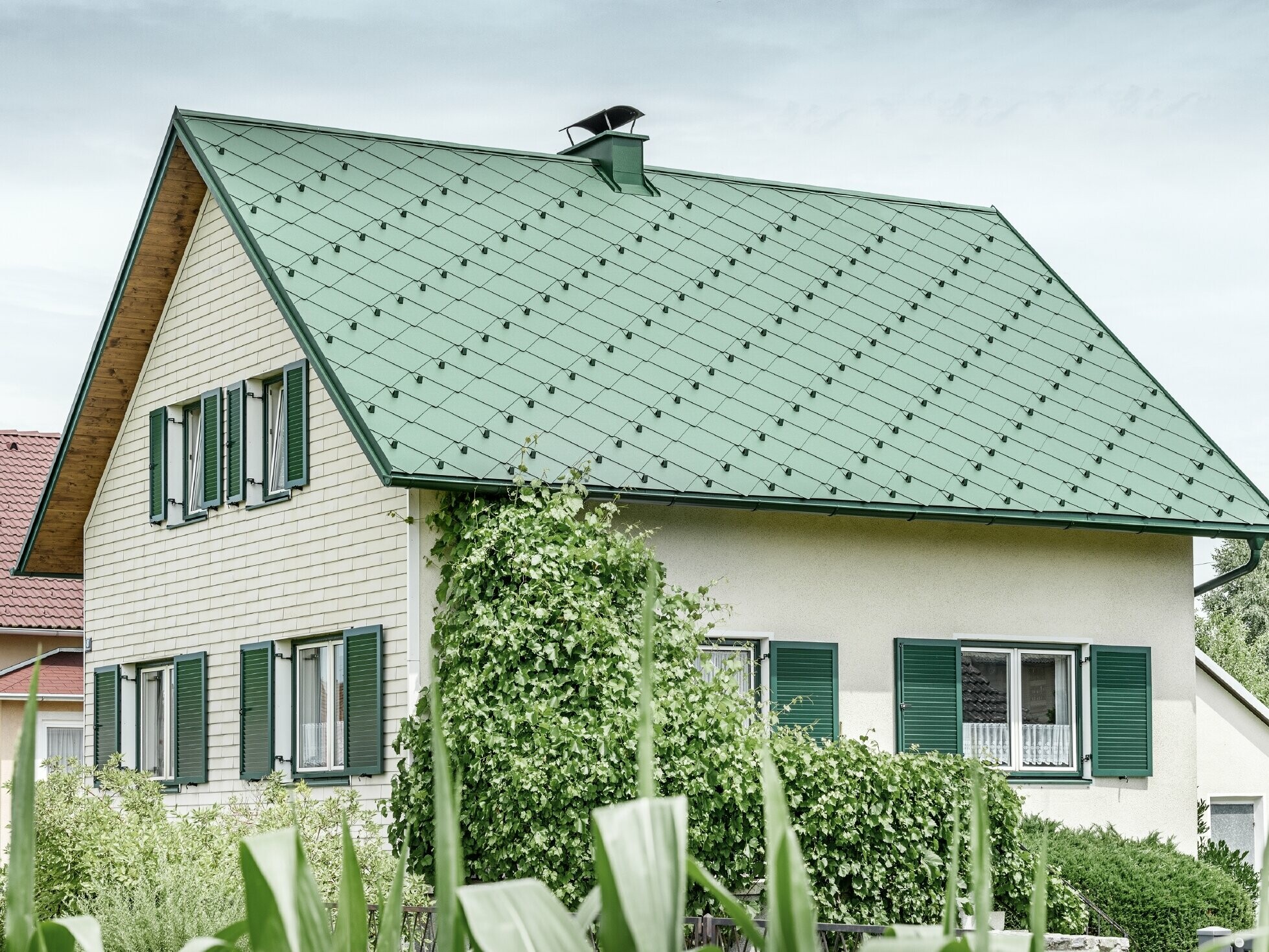 Toit à pignon de maison individuelle classique avec couverture en aluminium vert mousse et volets verts