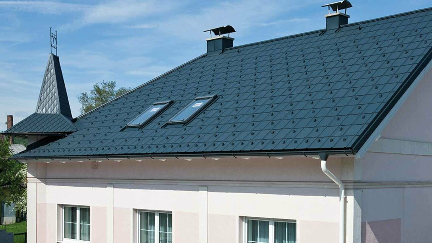 Maison après la rénovation de toiture à l’aide de tuiles PREFA, en Autriche. Auparavant fibrociment Eternit avec tourelle et façade rose