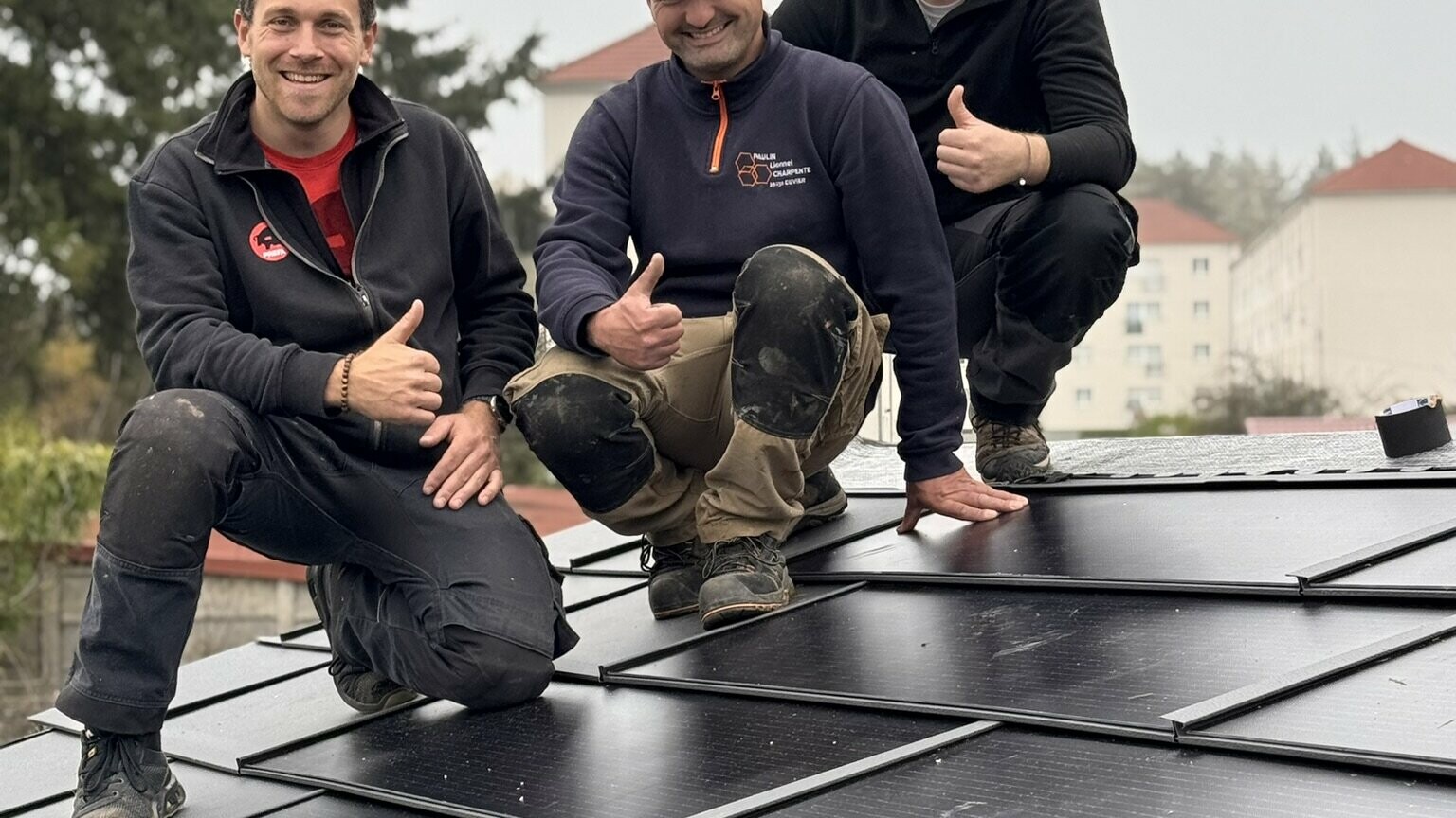 On aperçoit l'artisan Lionnel Paulin entouré de deux formateurs PREFA sur le toit en R.16, ils sourient devant la caméra