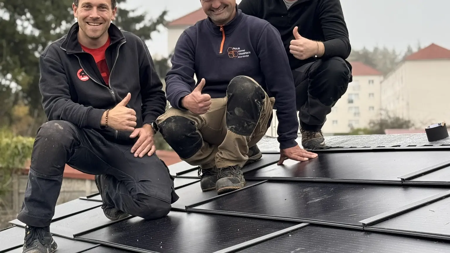 On aperçoit l'artisan Lionnel Paulin entouré de deux formateurs PREFA sur le toit en R.16, ils sourient devant la caméra