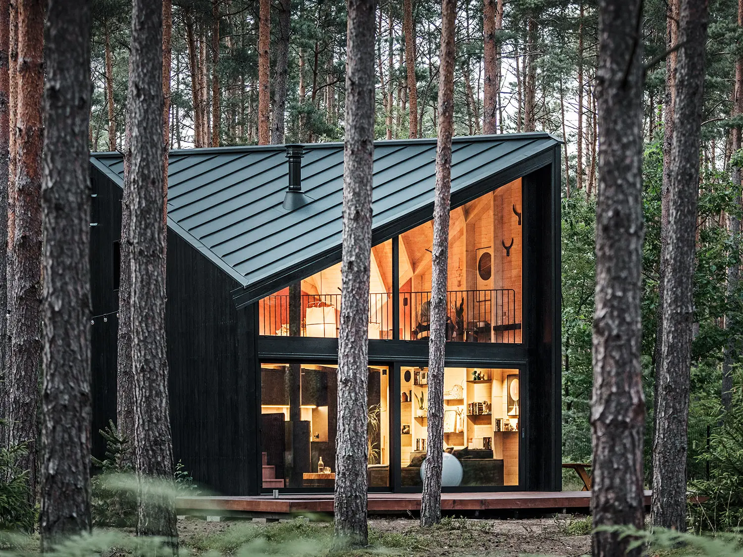 Vue latérale de la façade vitrée du bâtiment et de l'intérieur éclairé, inspiré par le style scandinave.