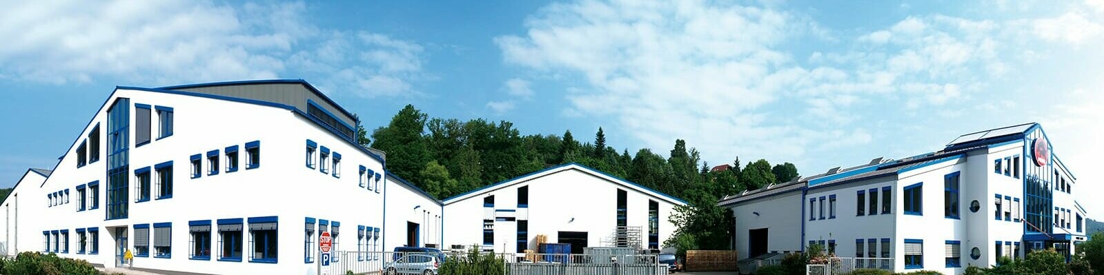 Bâtiment de la société PREFA avec façade blanche et fenêtres bleues