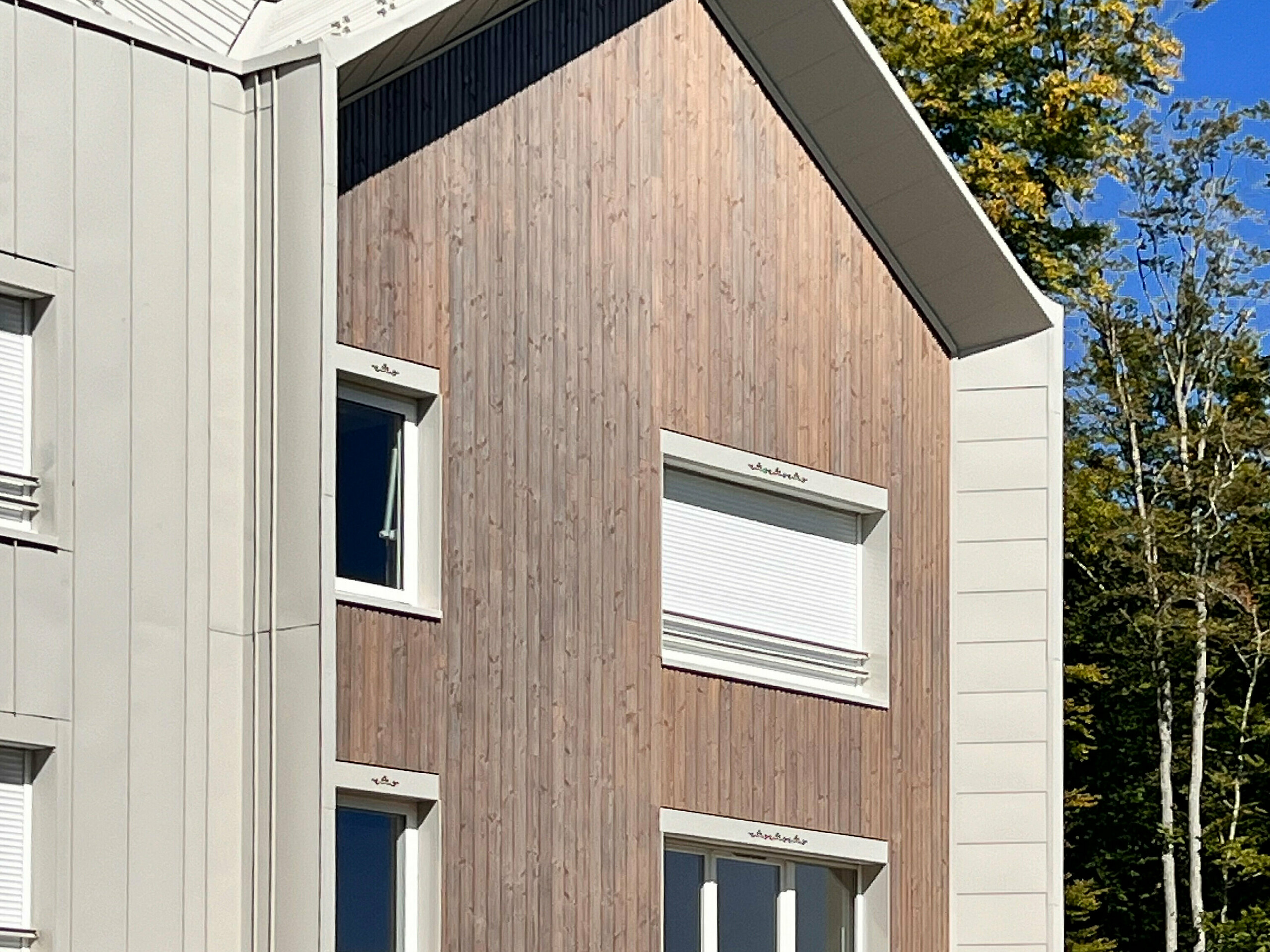Prise de vue latérale de la résidence attenant au château des Avenières, on voit la façade en bois et la couverture en aluminium. La teinte spéciale Dune se marie à merveille.