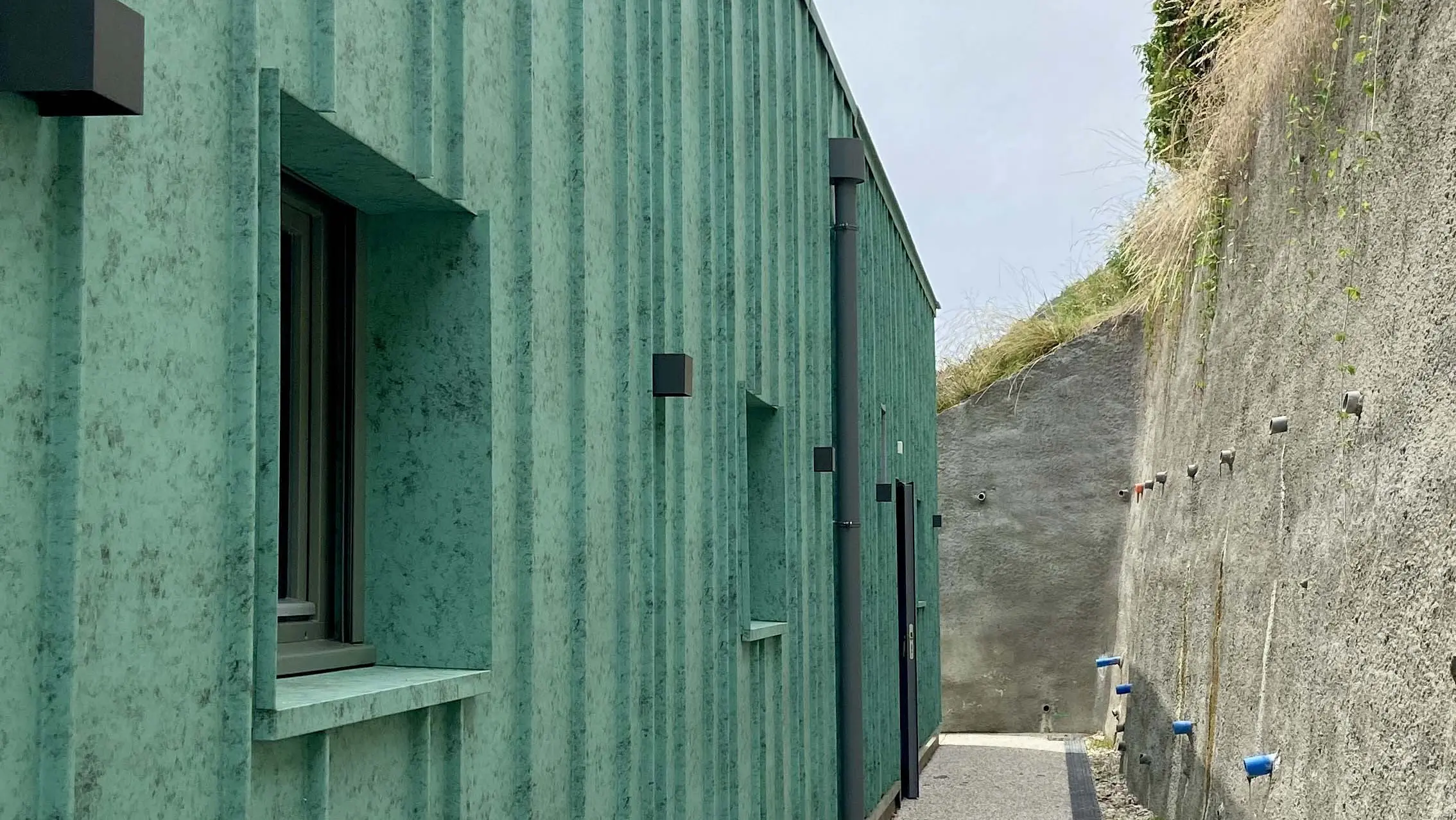 Vue de près de la façade de la nouvelle crèche des Adrets dont le bardage a été réalisé en joint debout en aluminium en pose aléatoire.