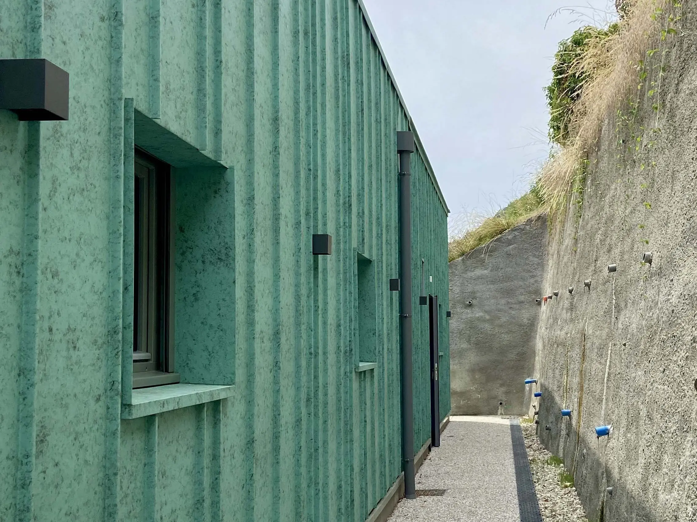 Vue de près de la façade de la nouvelle crèche des Adrets dont le bardage a été réalisé en joint debout en aluminium en pose aléatoire.