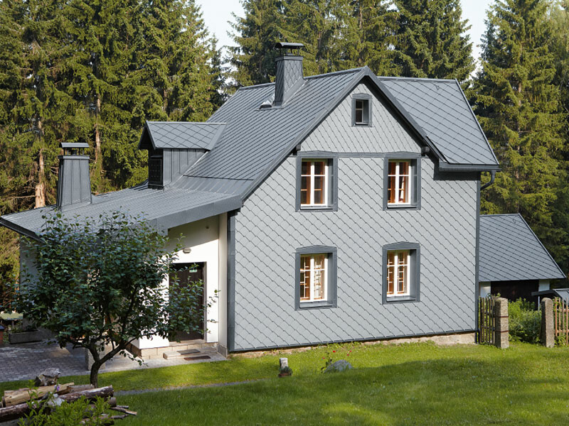 Maison individuelle dans un espace boisé avec façade en aluminium PREFA résistante aux intempéries en gris souris.